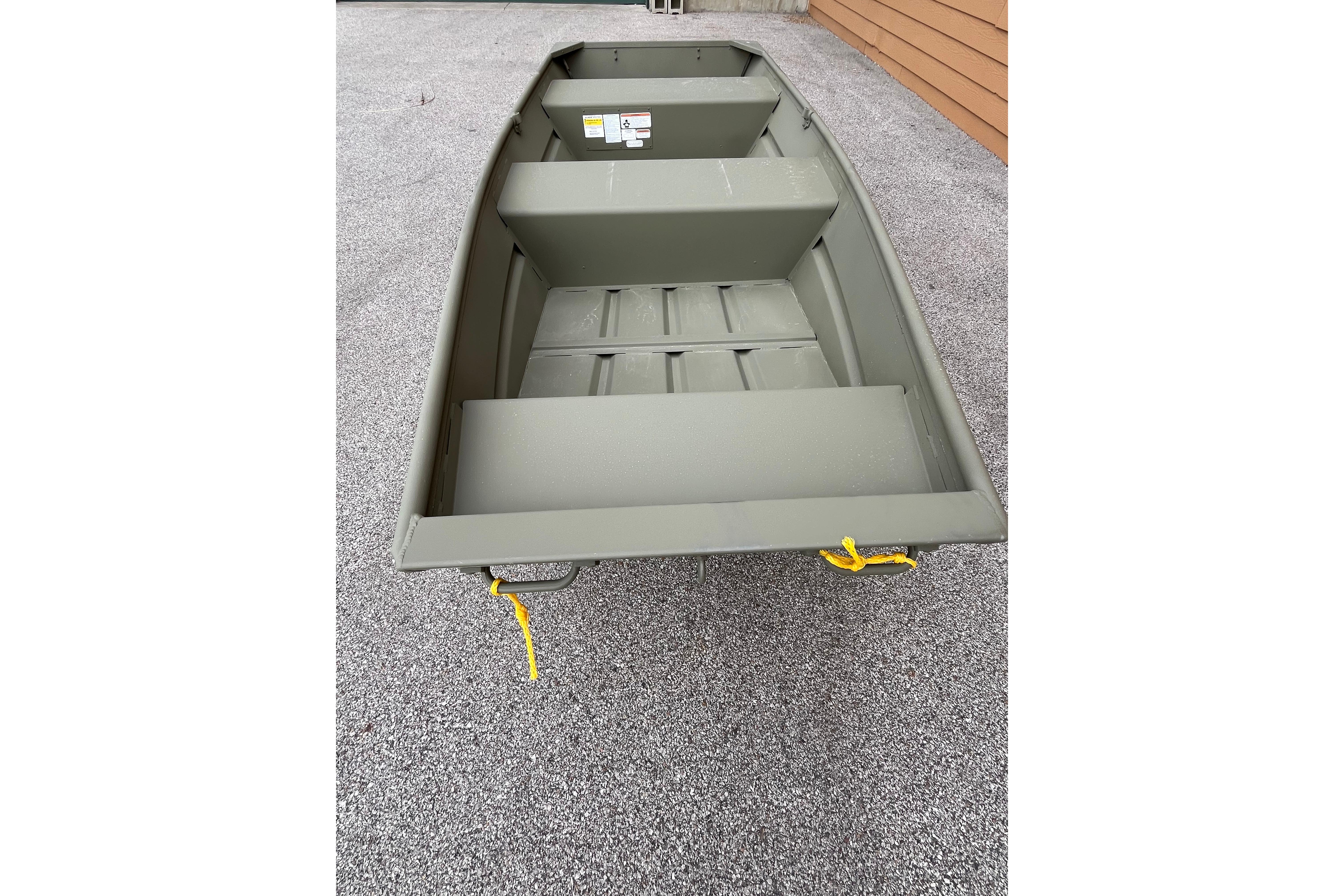 2026 Tracker Grizzly 12 Jon boat on gravel surface, showcasing interior seating and storage.