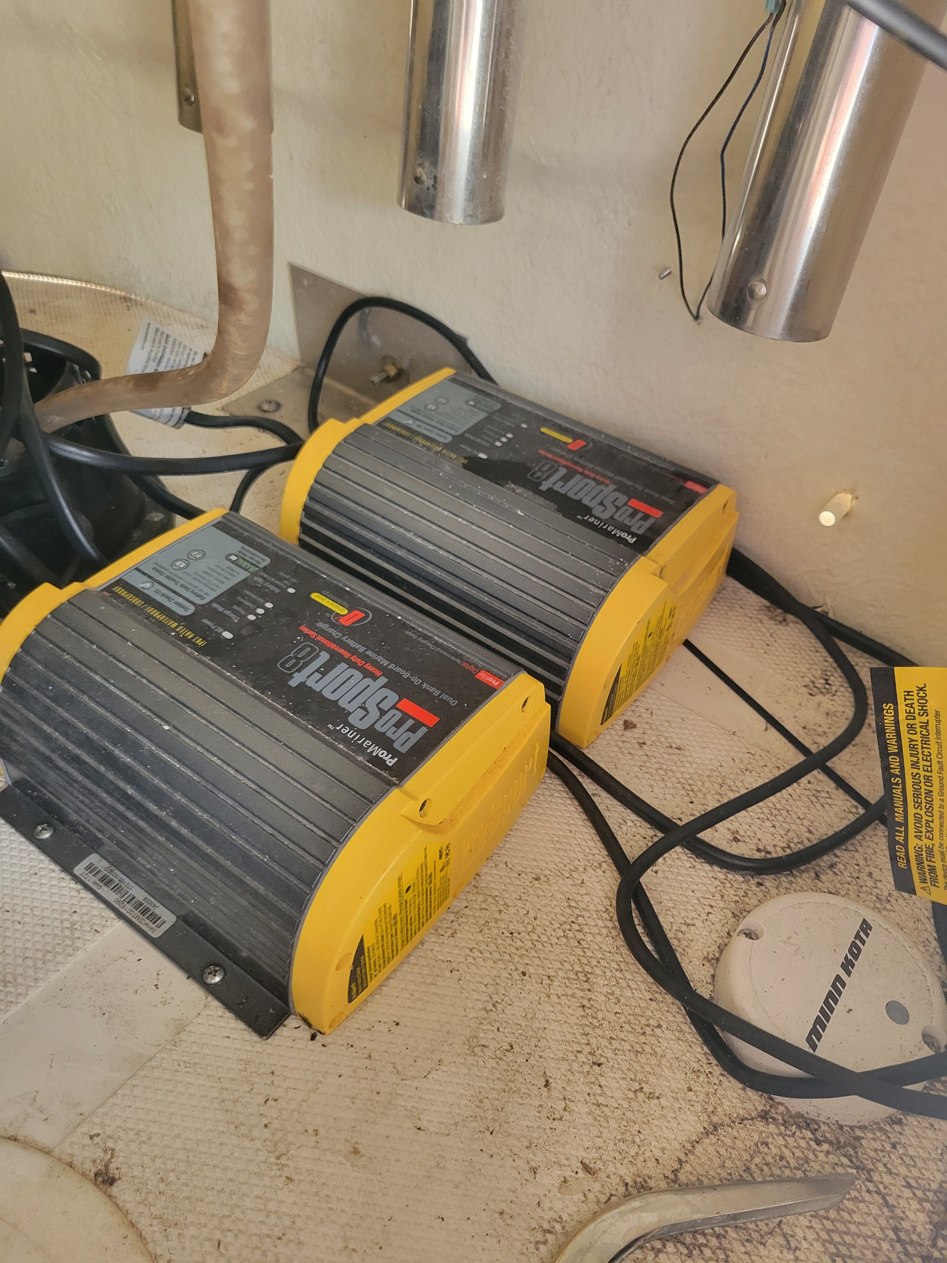Two yellow battery chargers are mounted inside a boat.