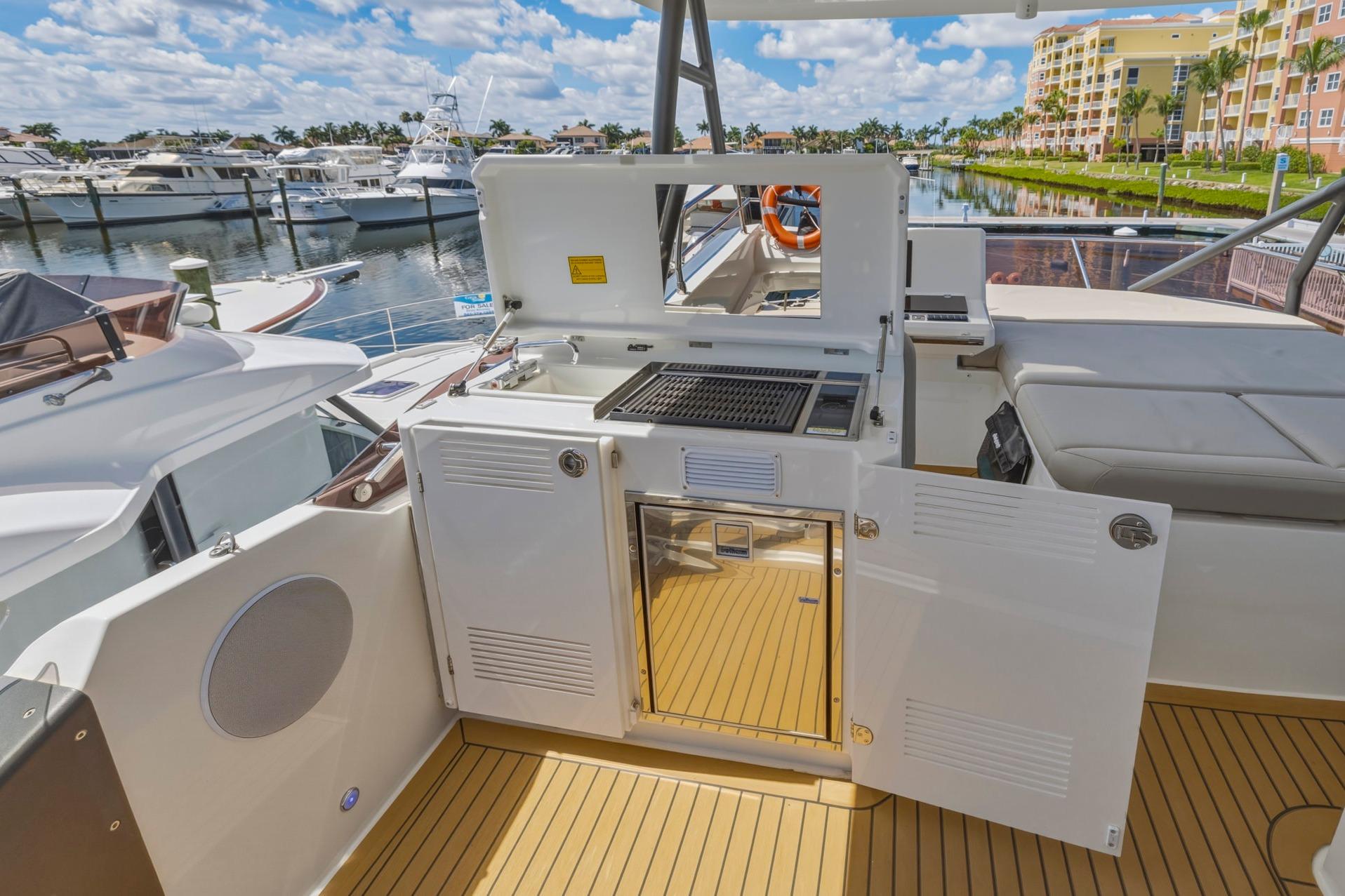 Luxury yacht Prestige 520, 2022 model, featuring an outdoor kitchen and scenic marina view.