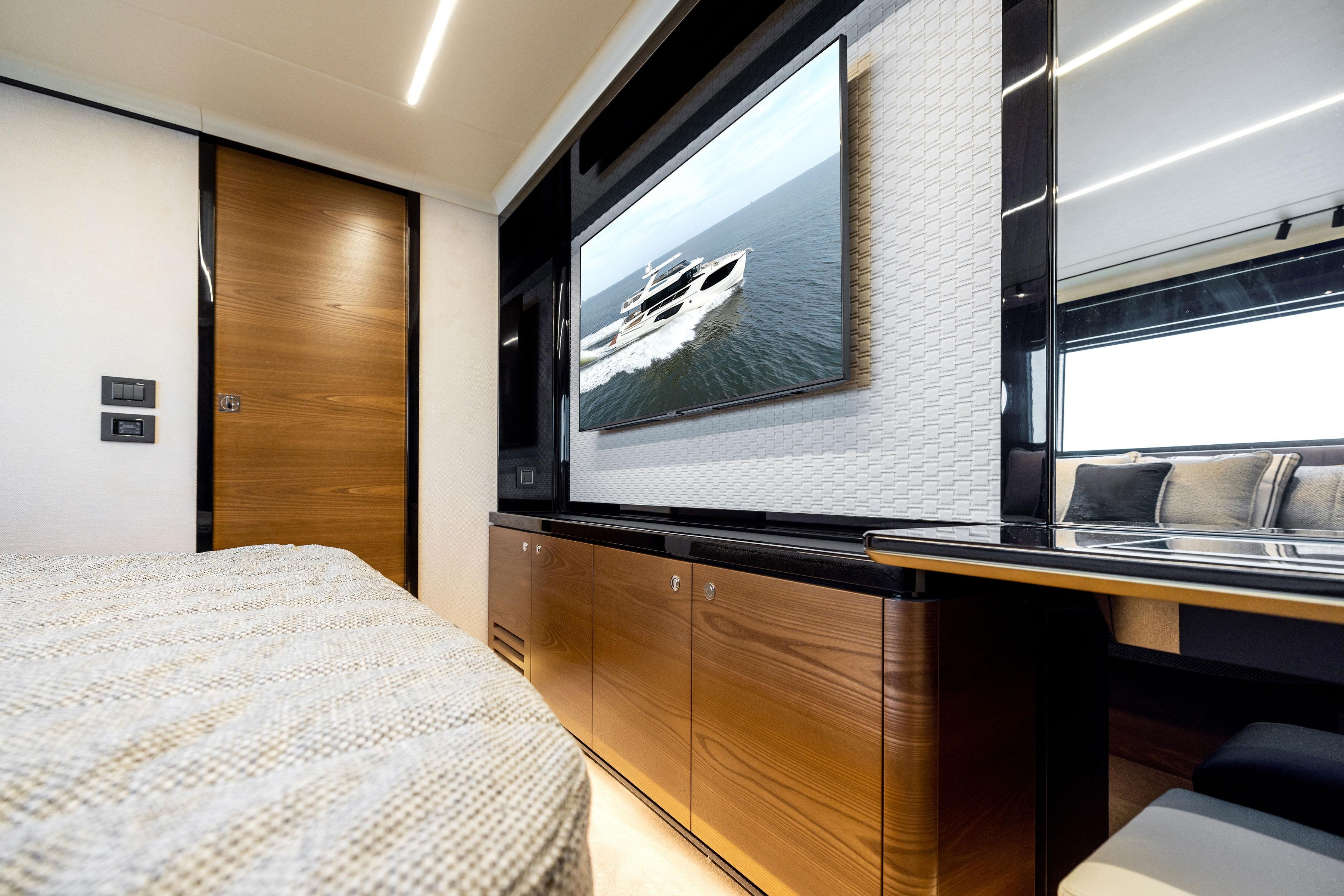 Luxurious interior of 2024 Absolute Navetta 64 yacht with modern design and large TV display.