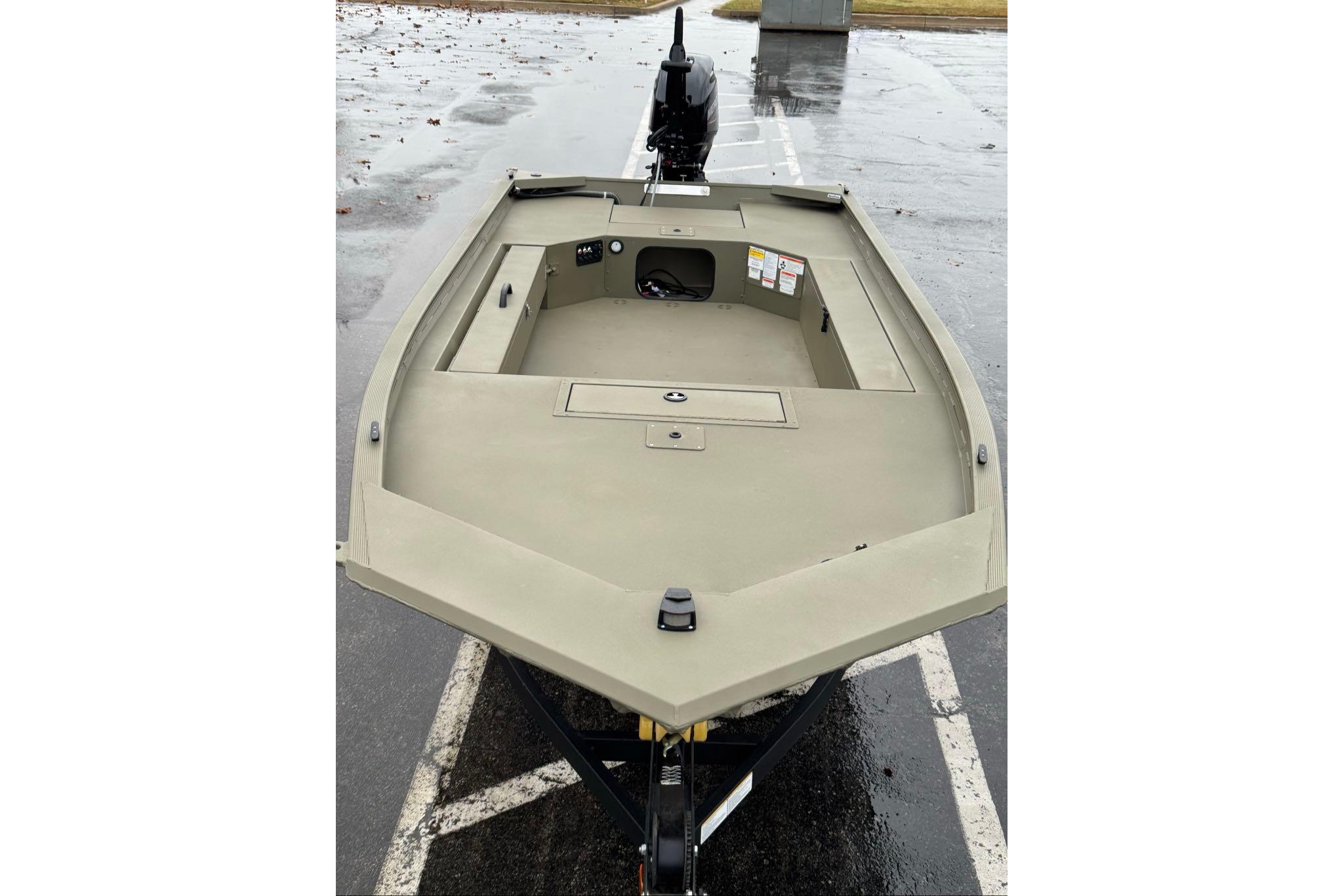 2026 Tracker Grizzly 1654 T Sportsman boat on wet pavement, showcasing spacious deck.