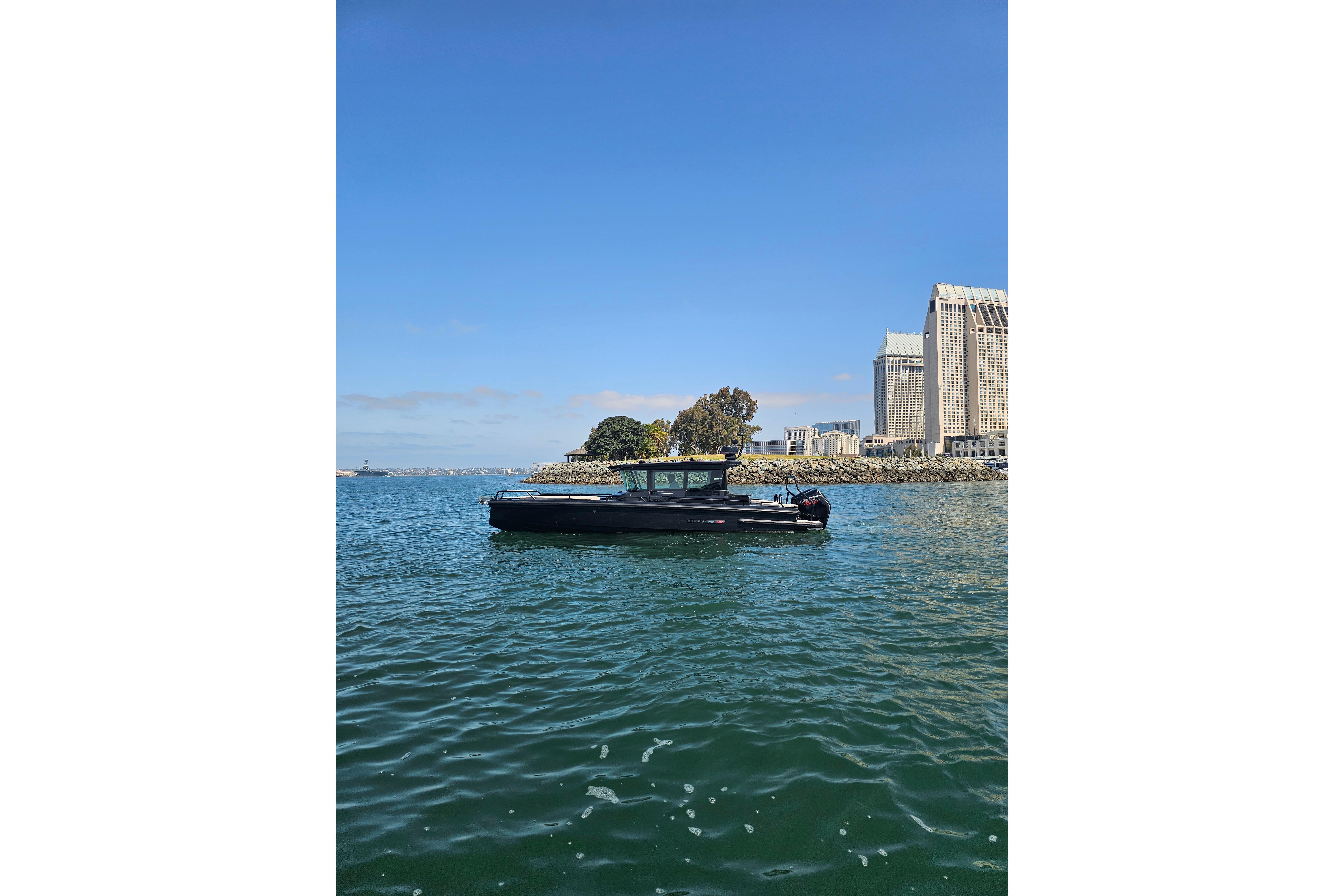 2023 BRABUS Shadow 500 Black Ops boat cruising near urban waterfront skyline.