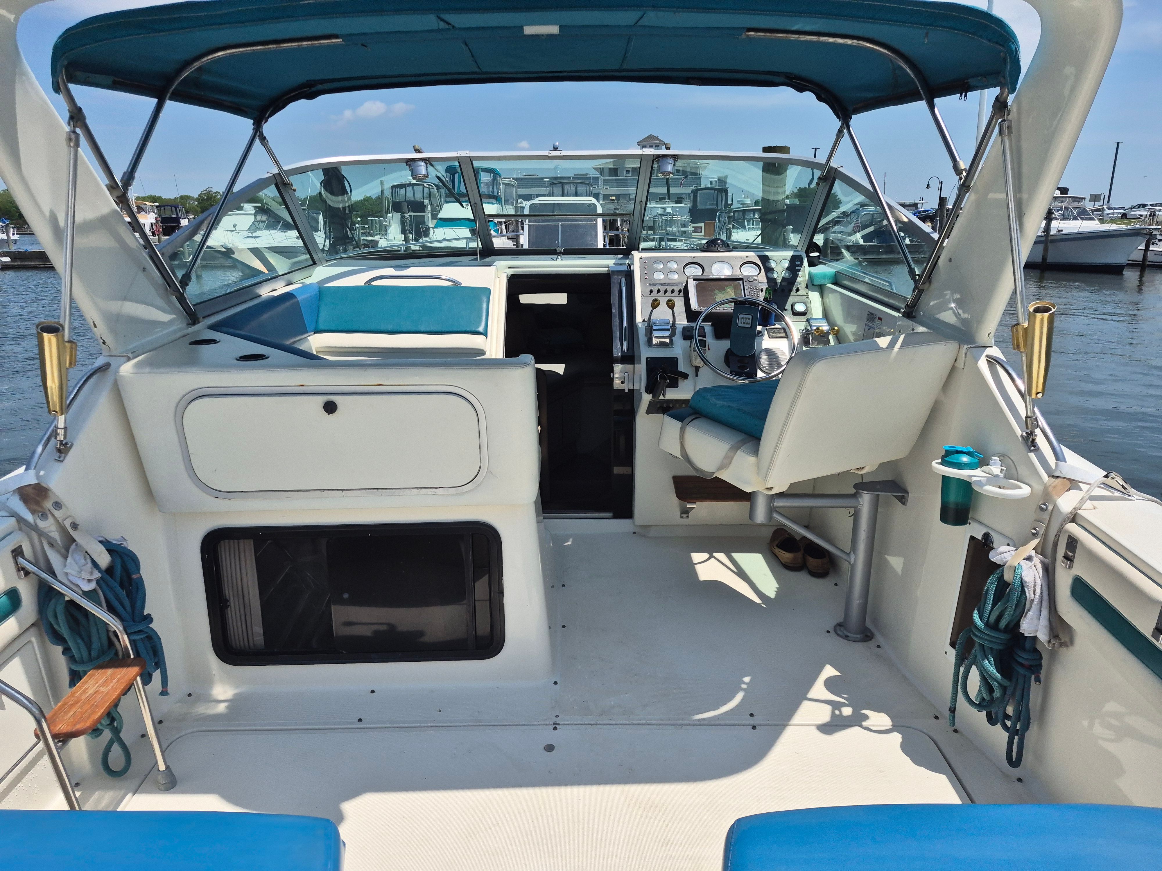 The cockpit of a 1989 Tiara Yachts Slickcraft with blue upholstery and a steering wheel.