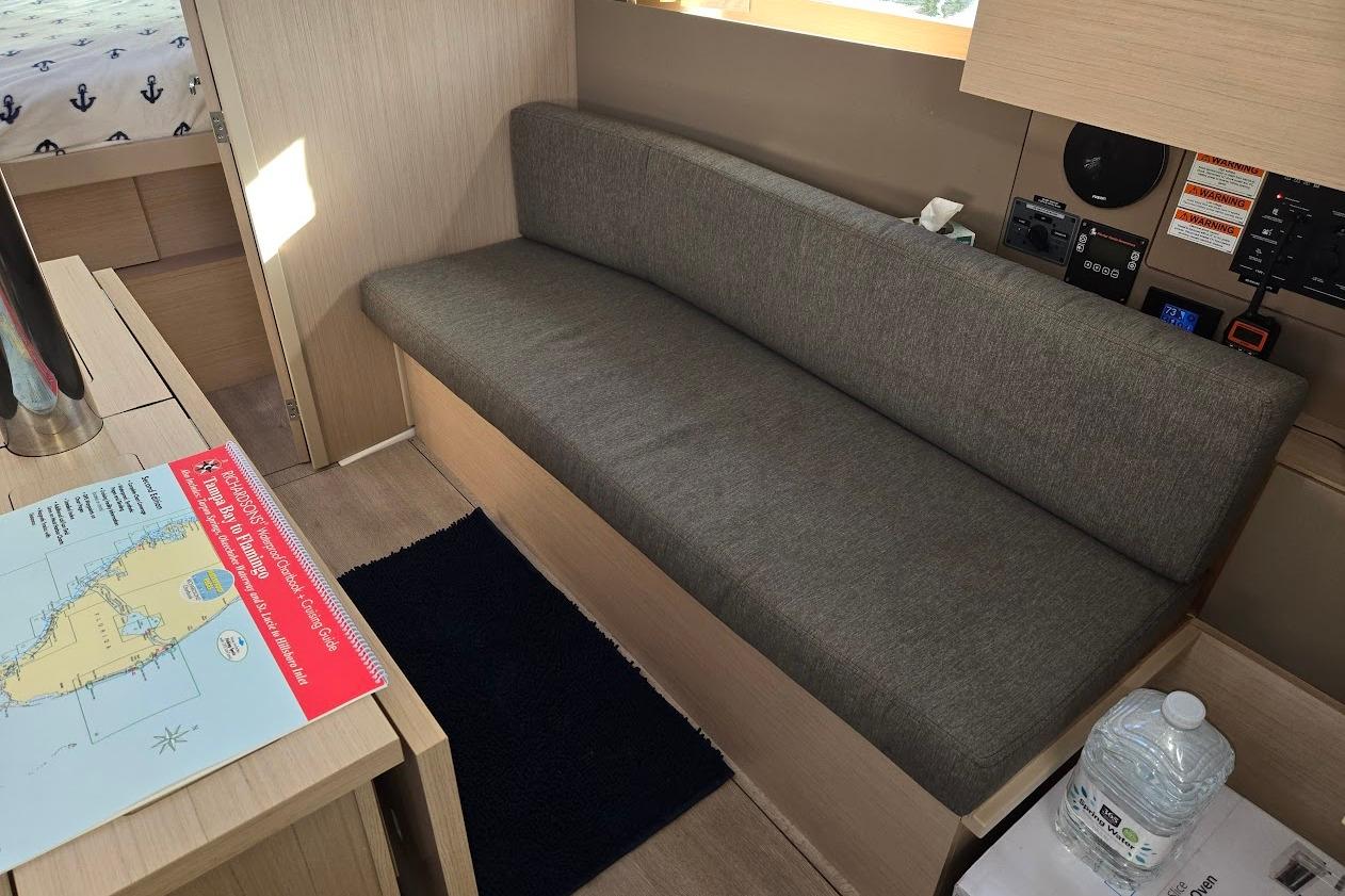 Interior of 2023 Beneteau Oceanis 38.1 yacht with gray sofa and navigation map.