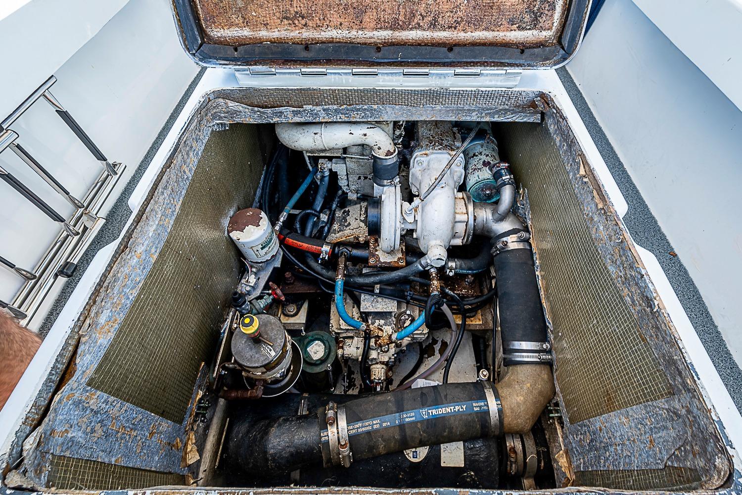 1969 custom engine compartment with visible components and hoses in a boat.