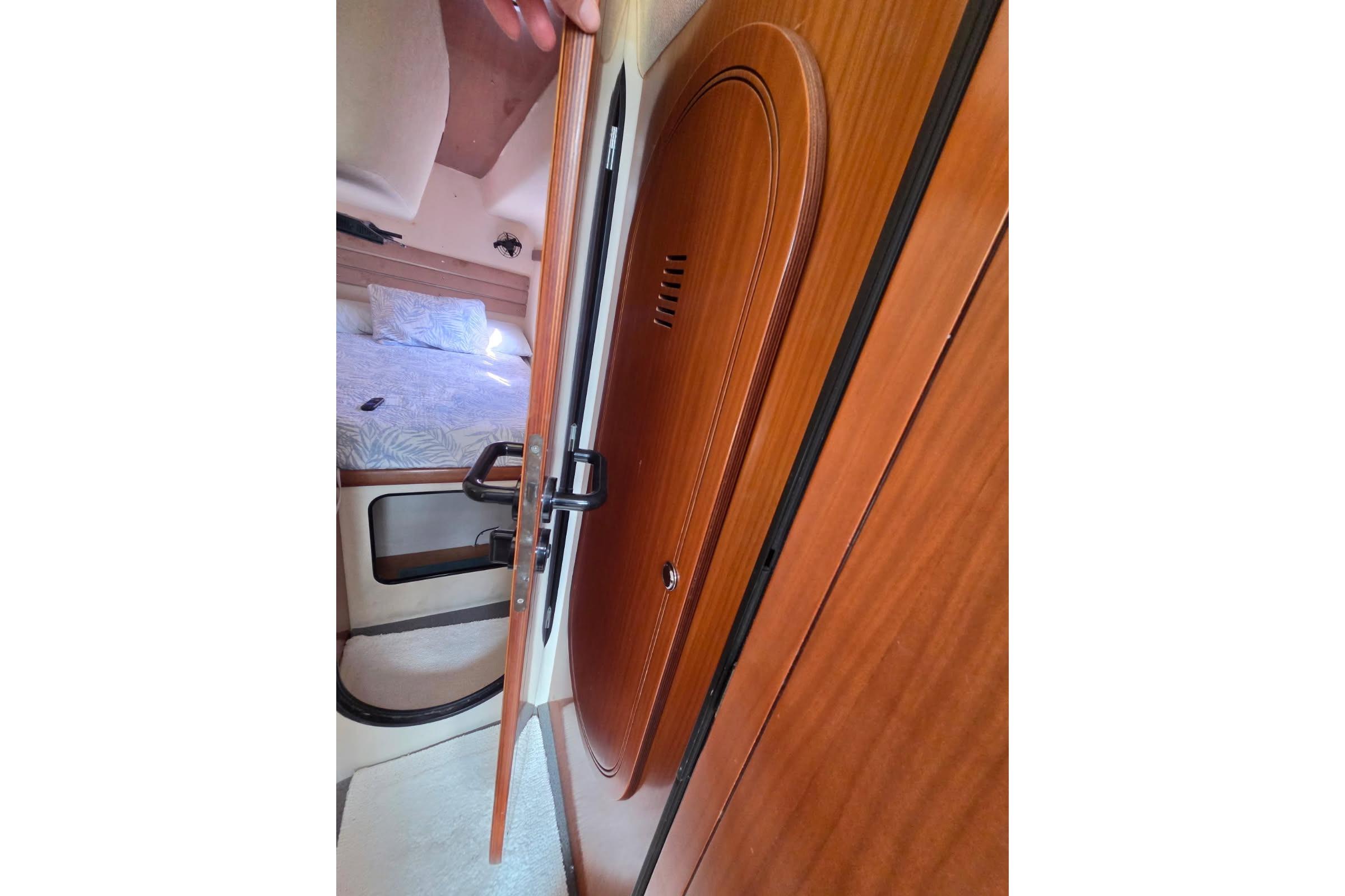 Interior cabin view of 2000 Fountaine Pajot Maryland 37 yacht with wooden door and bed.