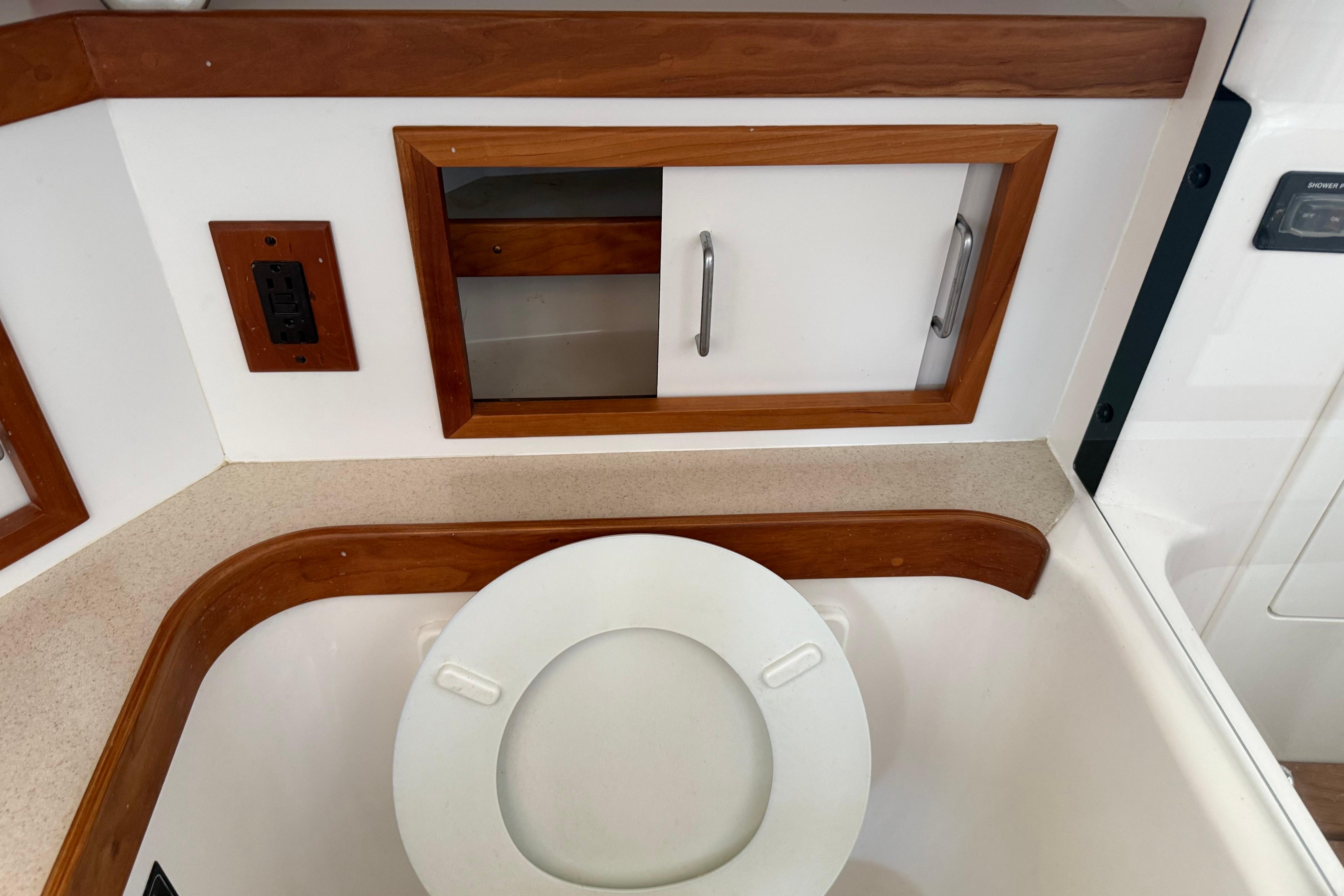 2004 Sabre 386 yacht bathroom with wooden trim and storage cabinet.