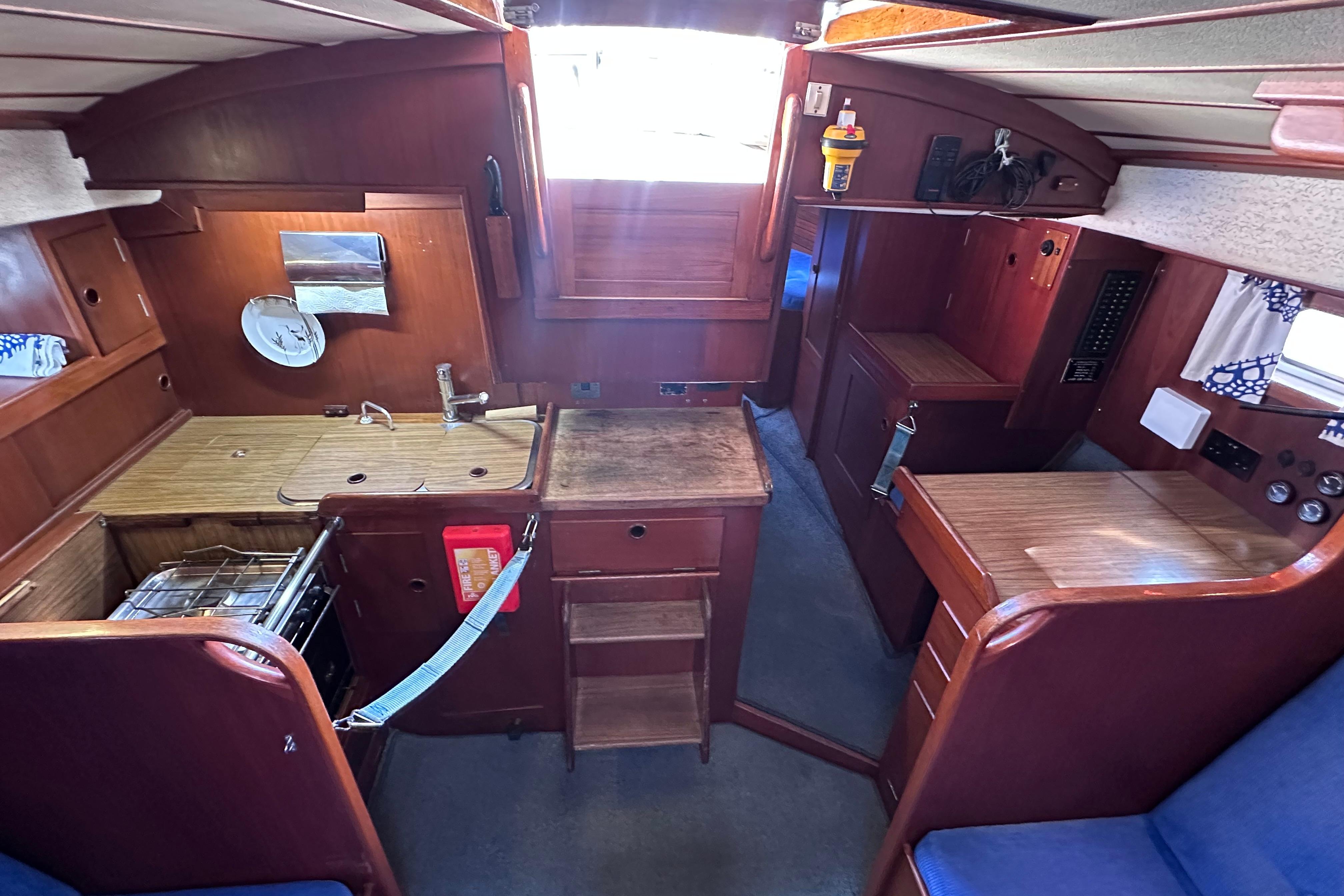 Interior of 1980 Hallberg-Rassy 352 sailboat with wooden cabinetry and compact kitchen area.