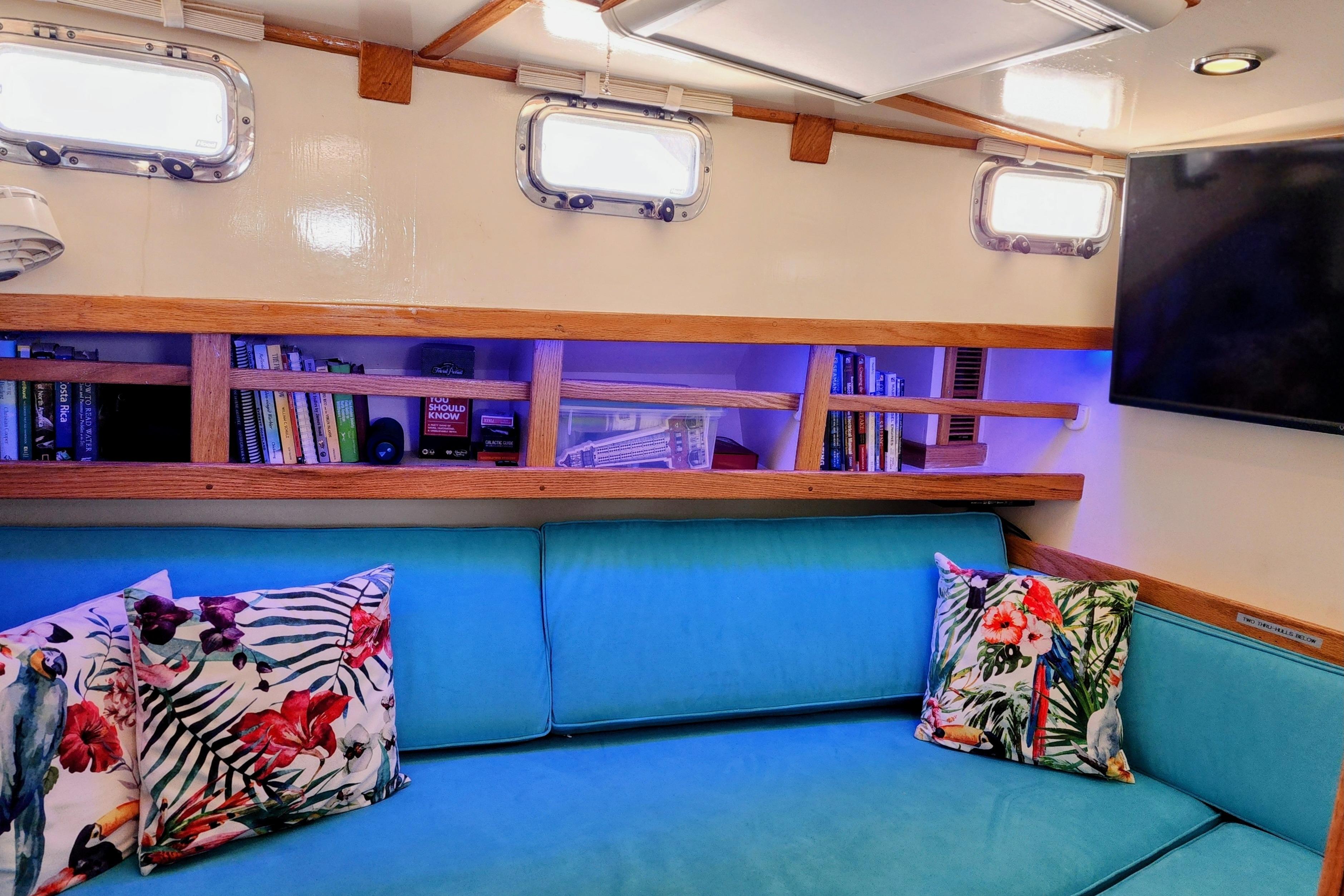 Interior of 1995 Benford Custom Pilothouse Cutter with vibrant cushions and bookshelves.