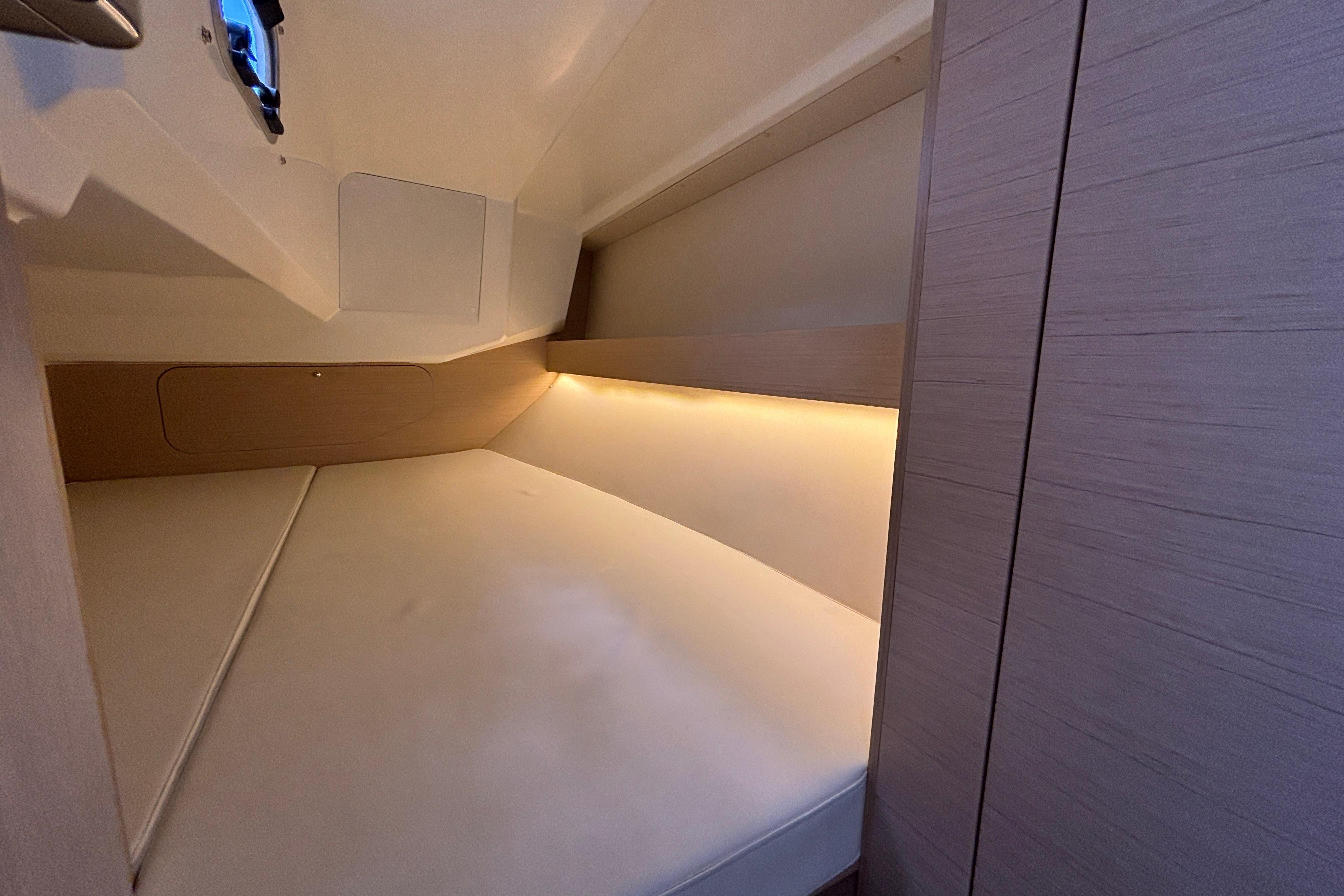 Cozy cabin interior of 2021 Beneteau Oceanis 30.1 yacht with soft lighting.