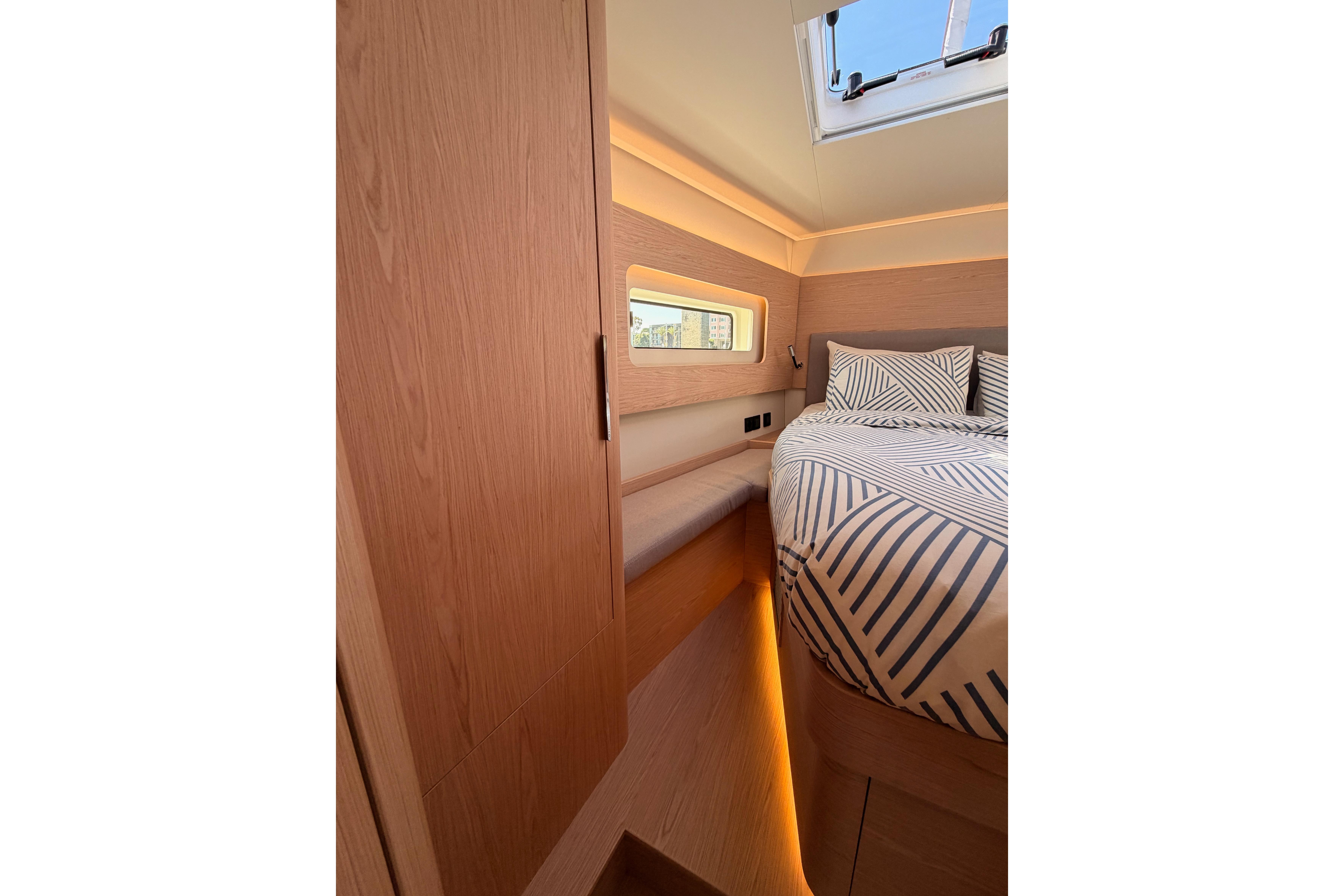 Luxurious cabin interior of 2022 Beneteau Oceanis Yacht 54 with modern bedding and wood finishes.