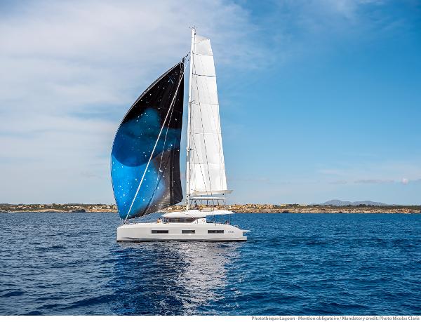 2025 Lagoon 55 catamaran sailing on open sea with vibrant blue and black sail.