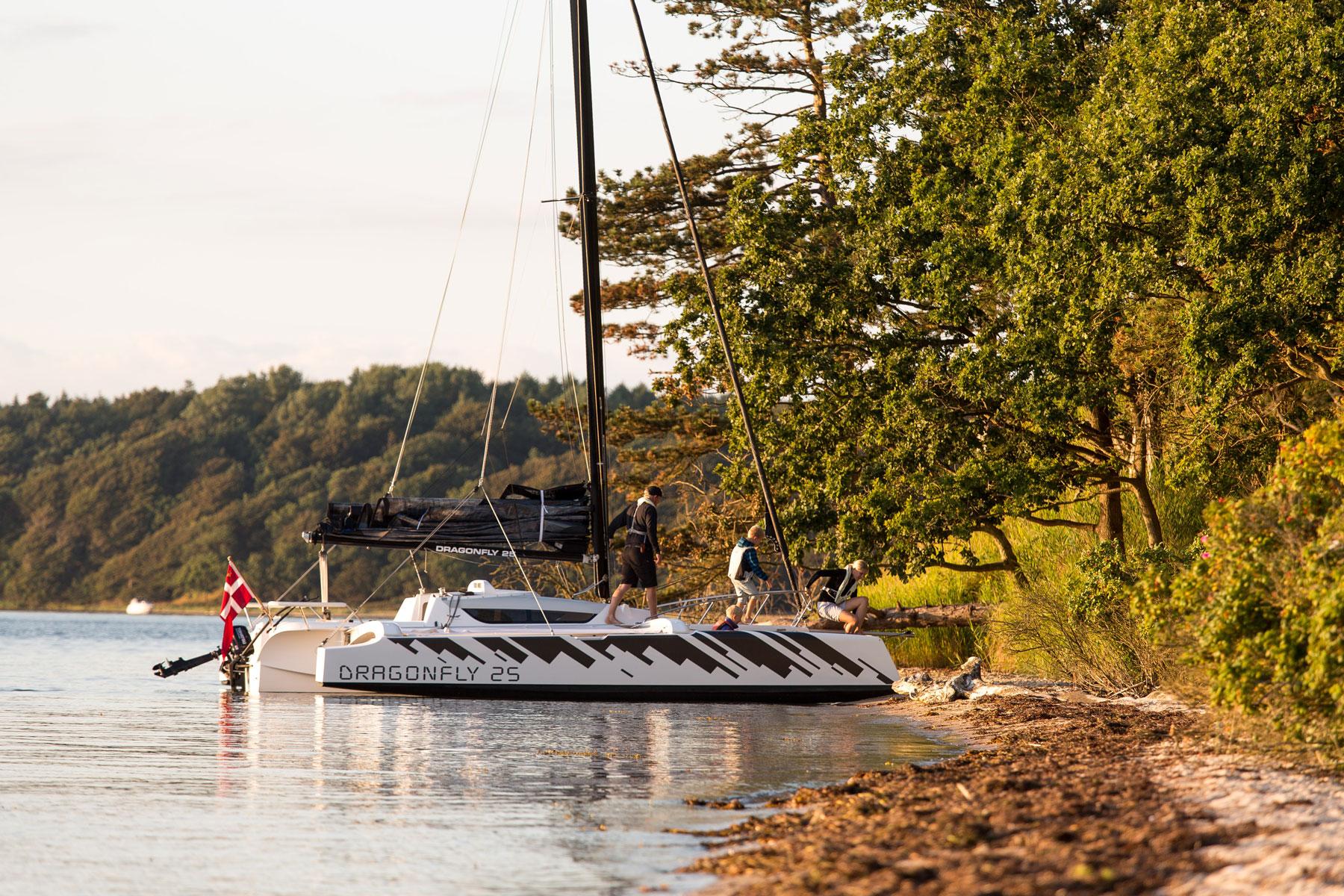 Sleek Dragonfly 25 sailboat moored by a scenic shoreline, 2025 model.