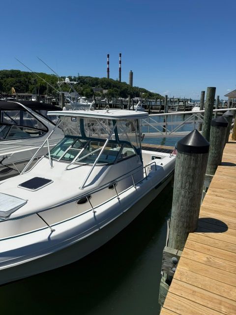 A 1995 Pro-Line 2950 Walkaround boat docked. Smokestacks are visible in the background.