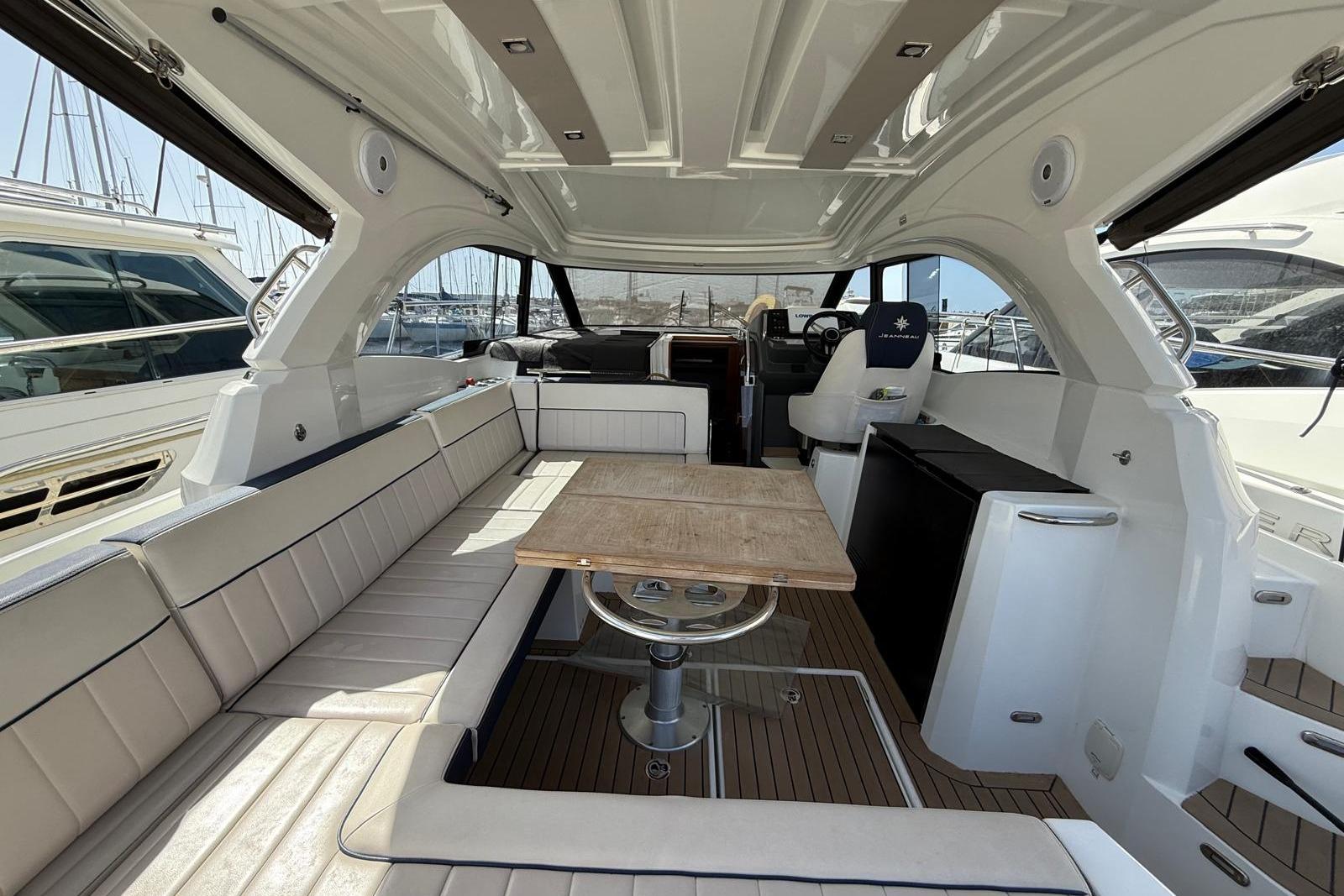 2019 Jeanneau Leader 33 yacht interior with seating, table, and helm station.