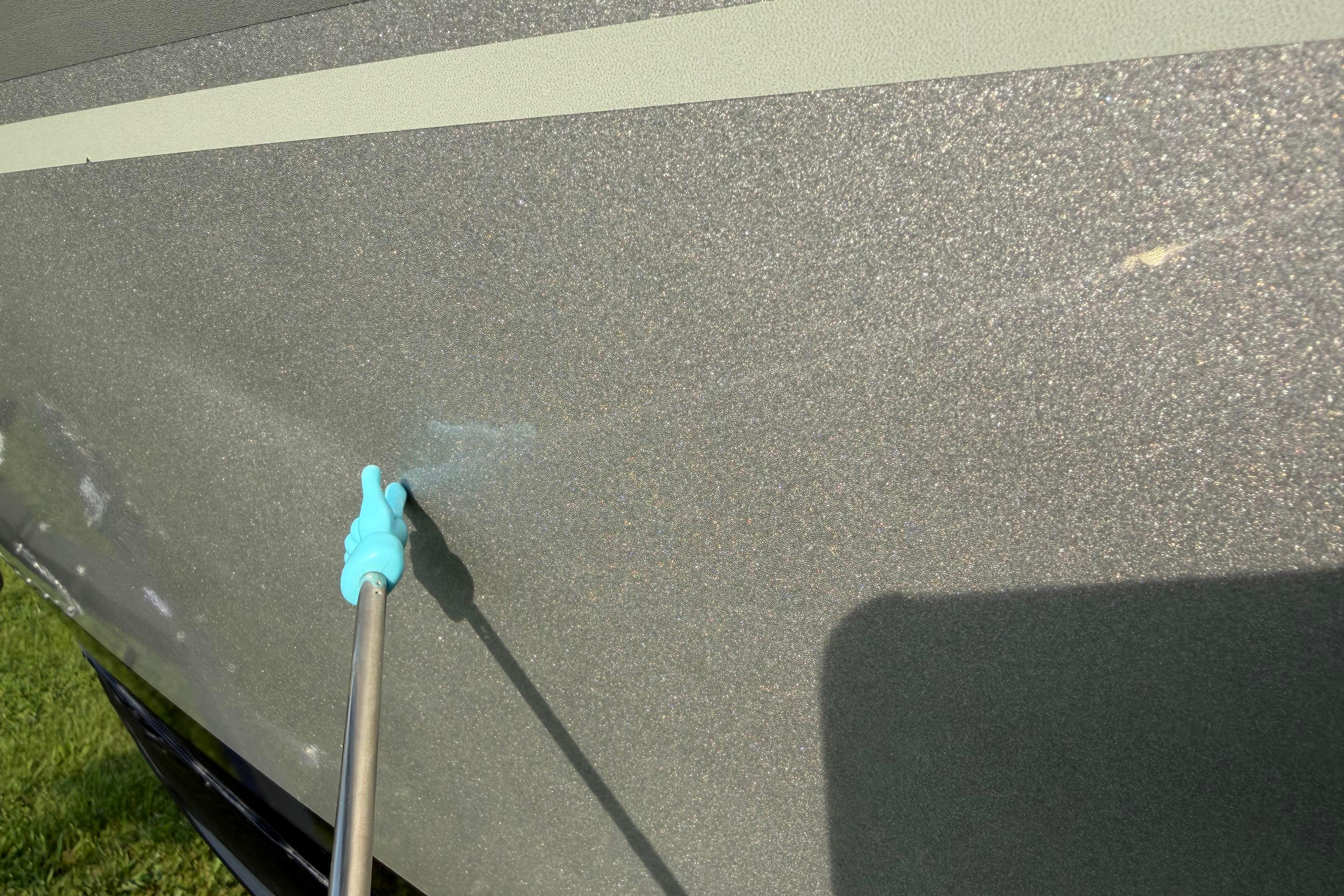 Cleaning the hull of a 2019 Alumacraft Trophy 205 boat with a spray nozzle.
