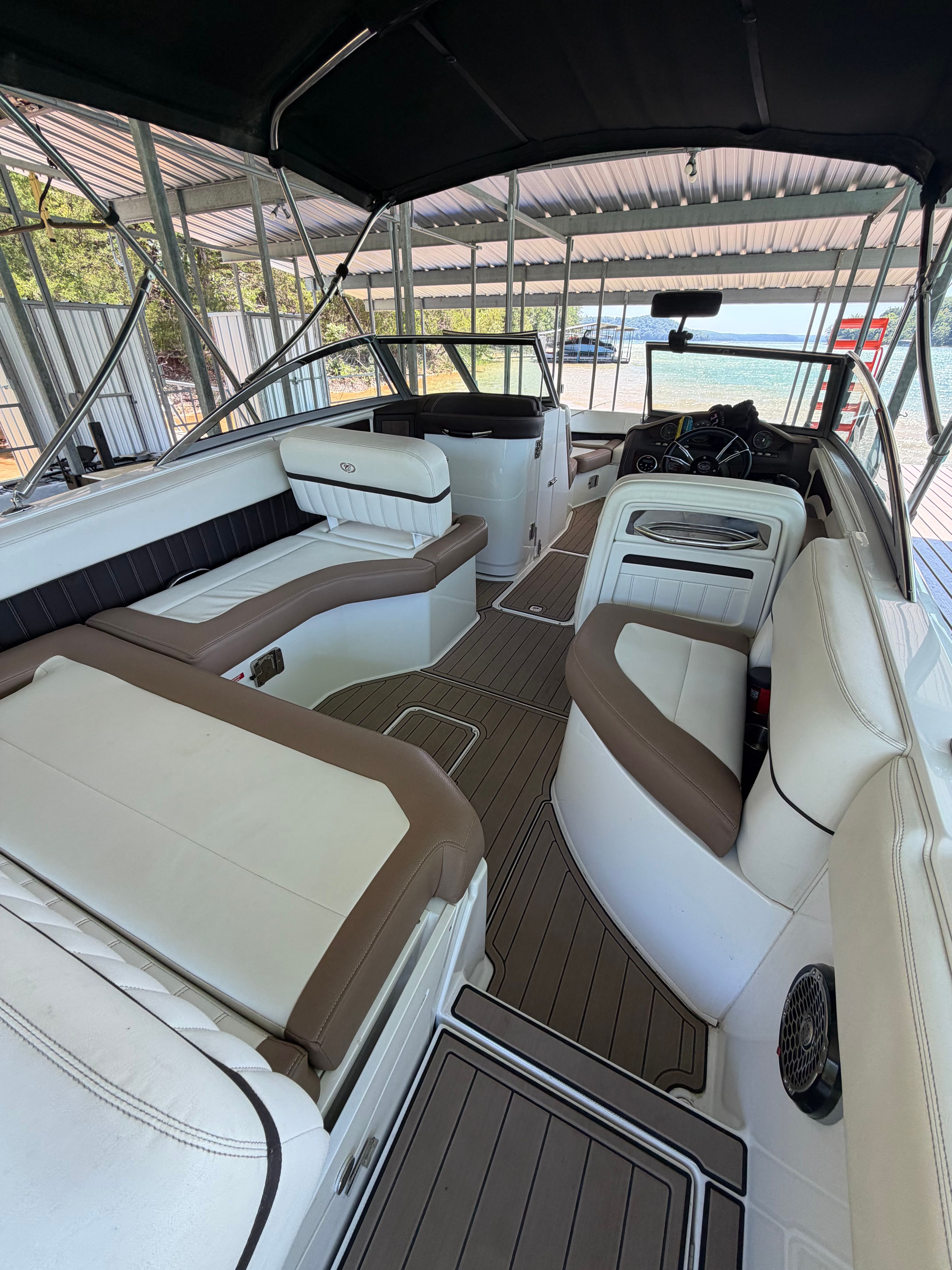 The interior of a Cobalt boat with white and brown seating, under a covered area.