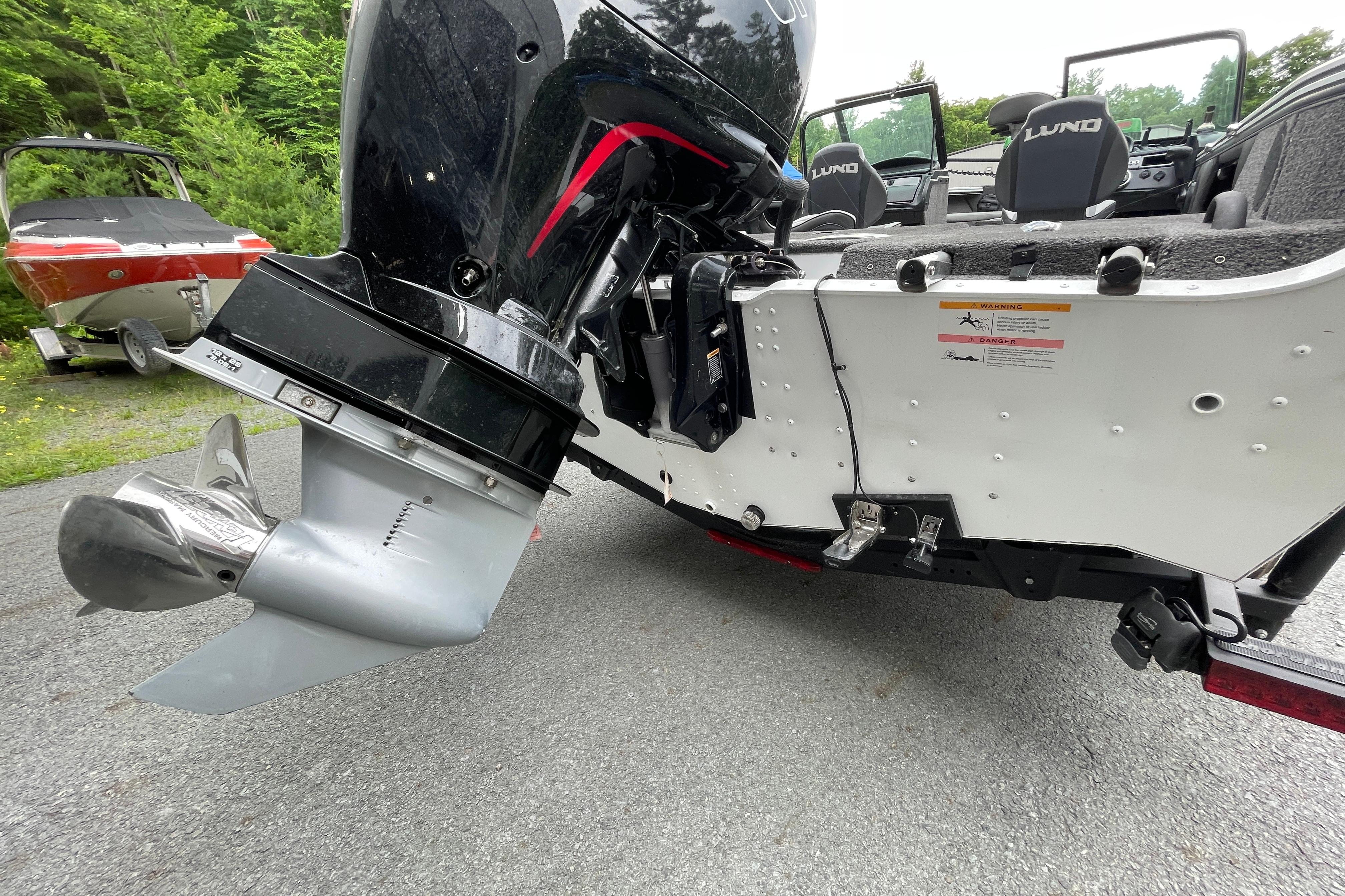 2022 Lund 1875 Crossover XS boat with powerful outboard motor, parked on a driveway.