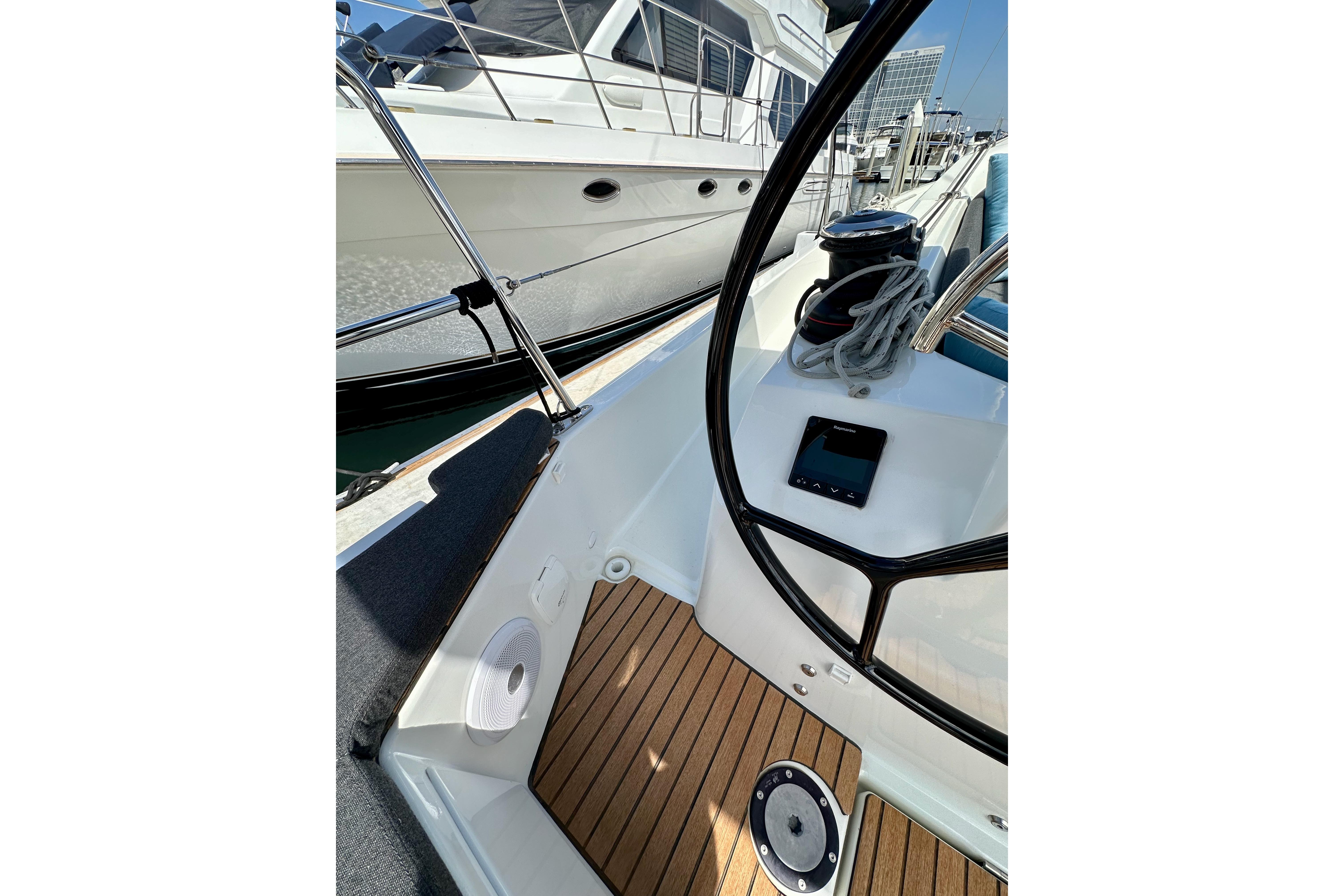 2024 Jeanneau Sun Odyssey 410 cockpit with steering wheel and wooden deck details.