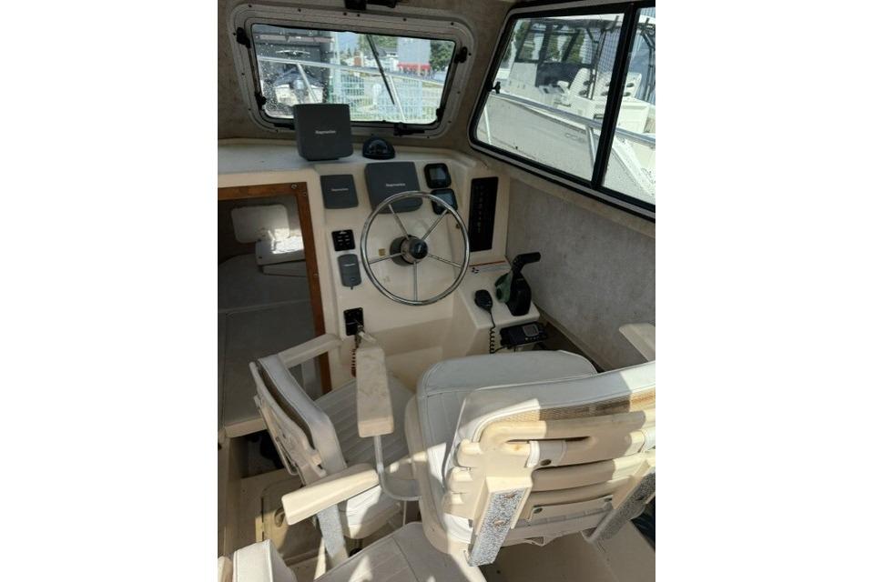 Interior of a 2006 Parker 2520 SL Sport Cabin boat, featuring steering wheel and controls.
