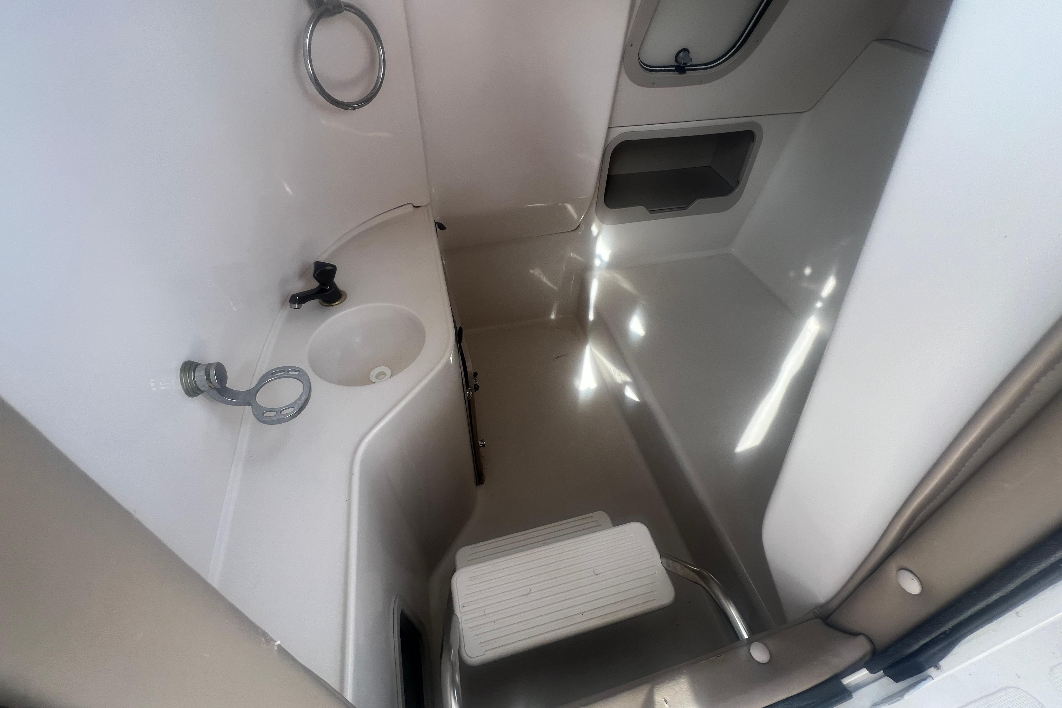 Interior of 2002 Hurricane SunDeck 260 OB boat, featuring compact bathroom amenities.