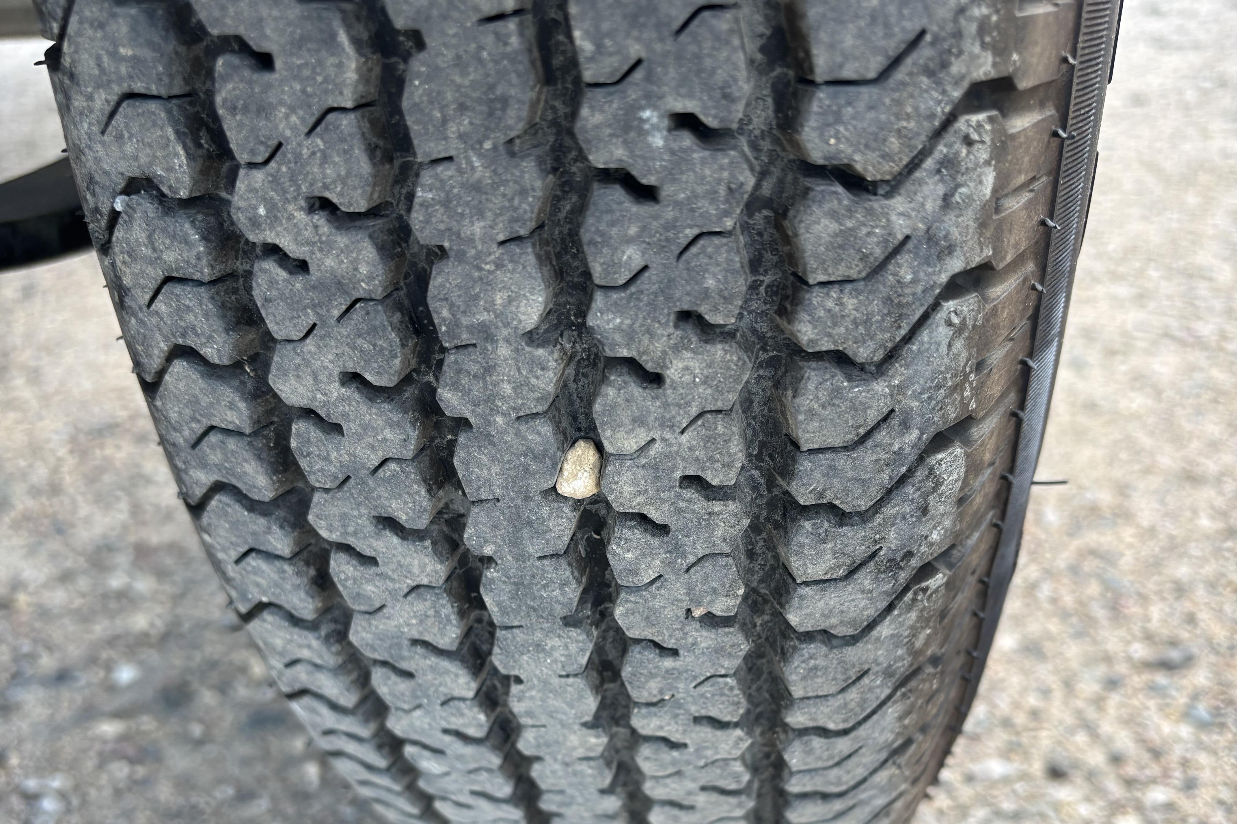 Close-up of a 2021 Tracker Pro Guide V-16 WT tire with a small stone in the tread.