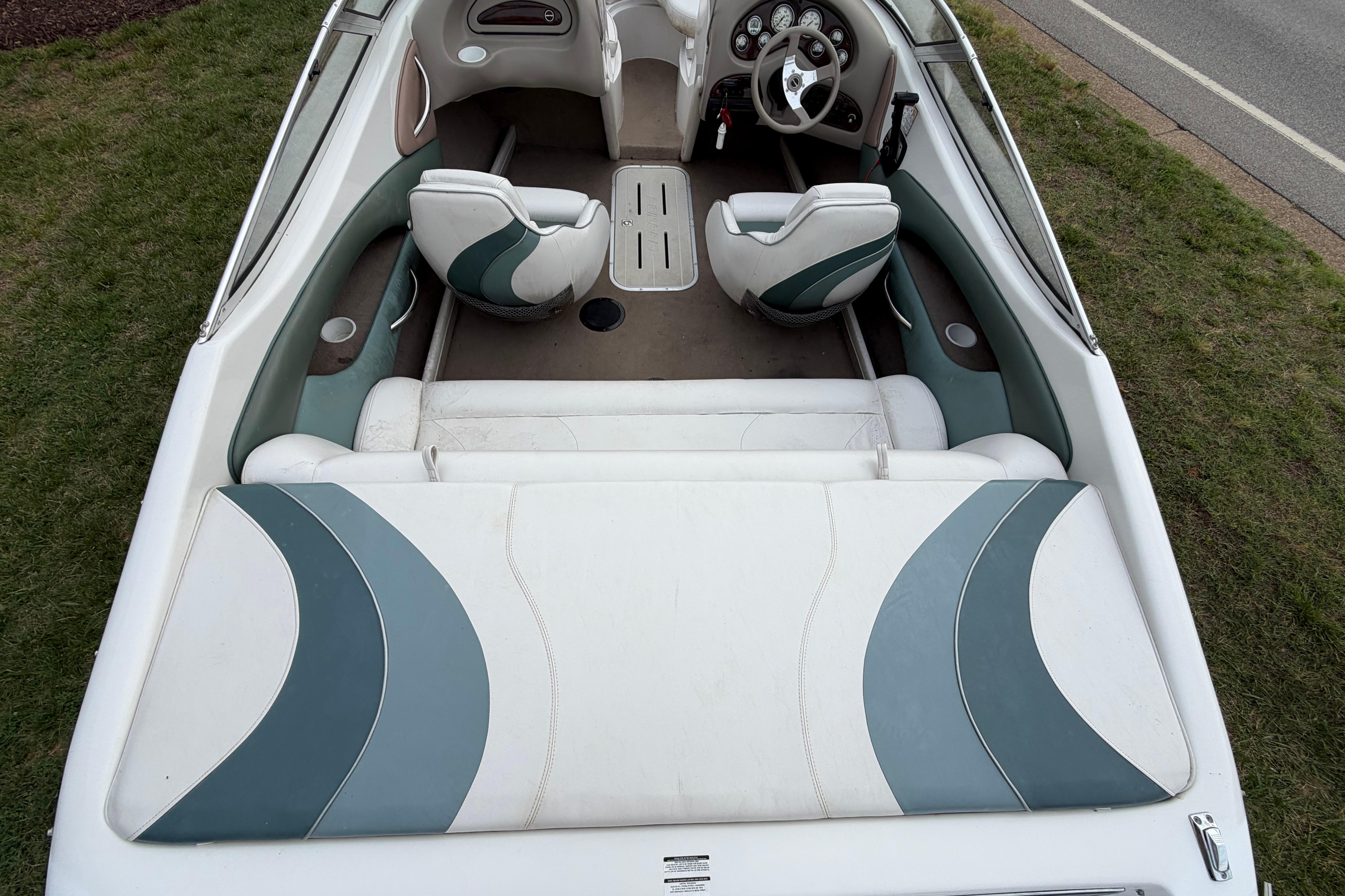 2001 Ebbtide Campione 190 boat interior with white and teal seating, steering wheel, and dashboard.