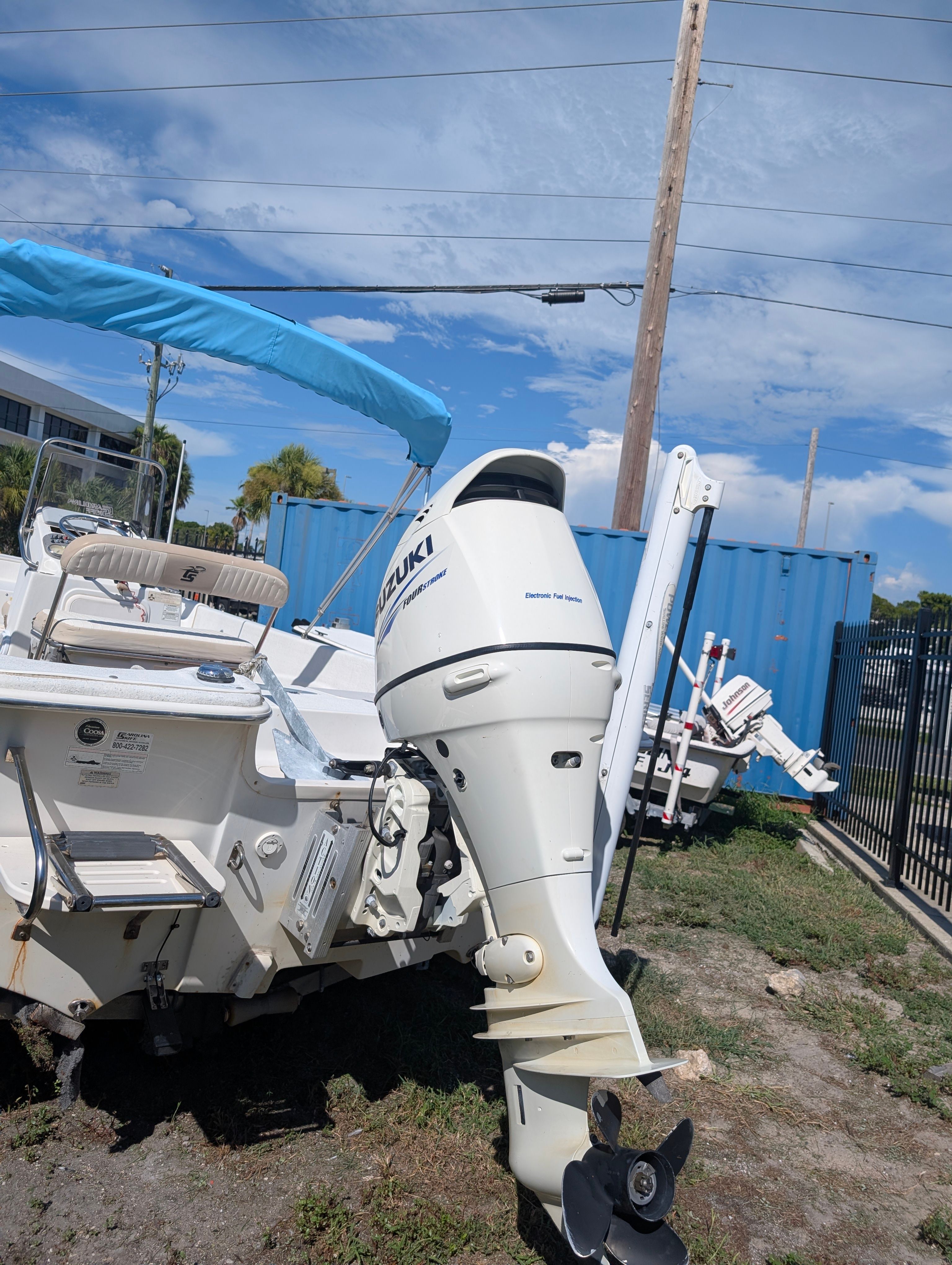 A 2016 Carolina Skiff 198 DLV with a Suzuki outboard motor, parked on grassy terrain.