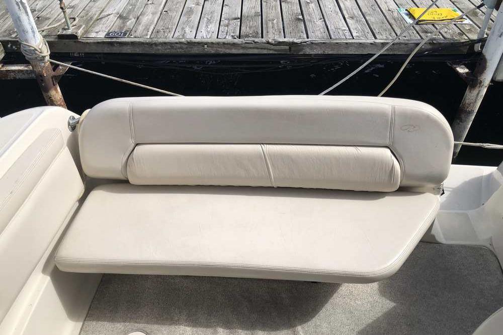 White seating on a 1999 Regal Commodore 2760 boat docked by wooden pier.