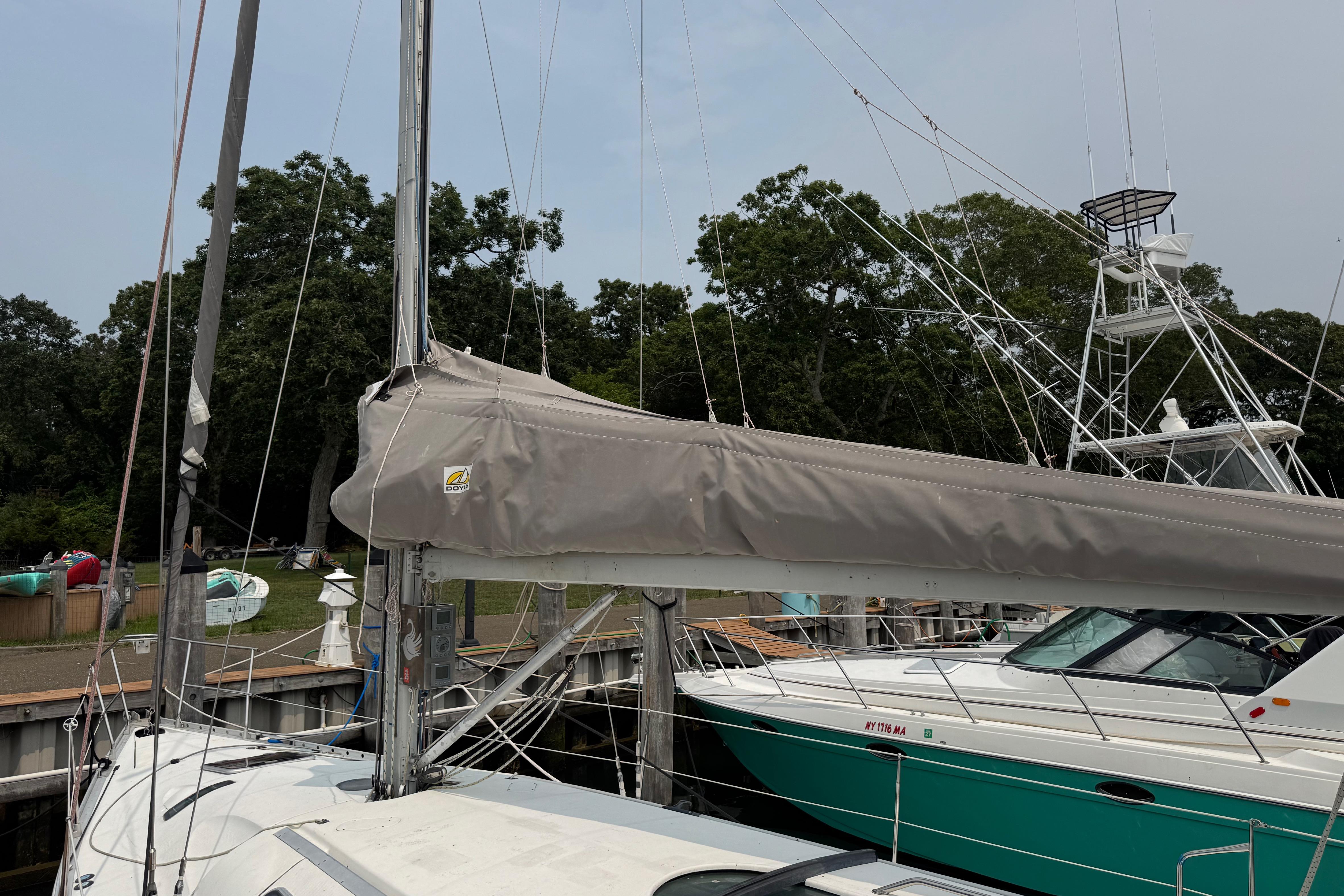 1989 Beneteau First 41s5 sailboat docked, featuring covered mainsail and nearby motorboat.
