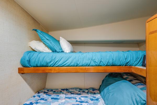 Bunk beds with blue bedding in a 1999 Viking 47 Convertible yacht cabin.