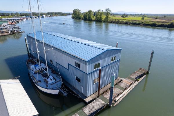 Aerial view of 1985 Custom Larson Boathouse with sailboat on a serene river.
