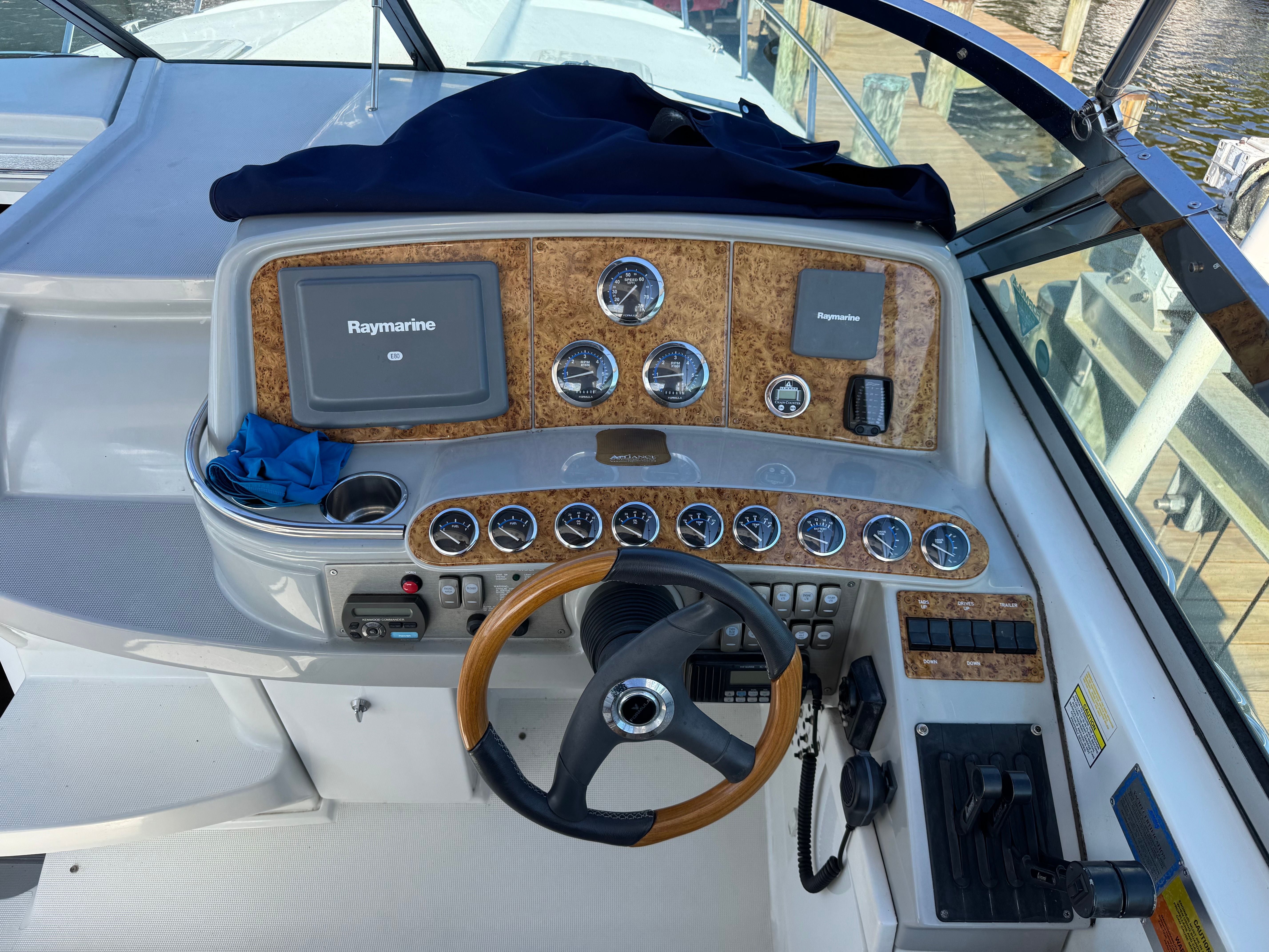 The cockpit of a boat with wood paneling and Raymarine screens.