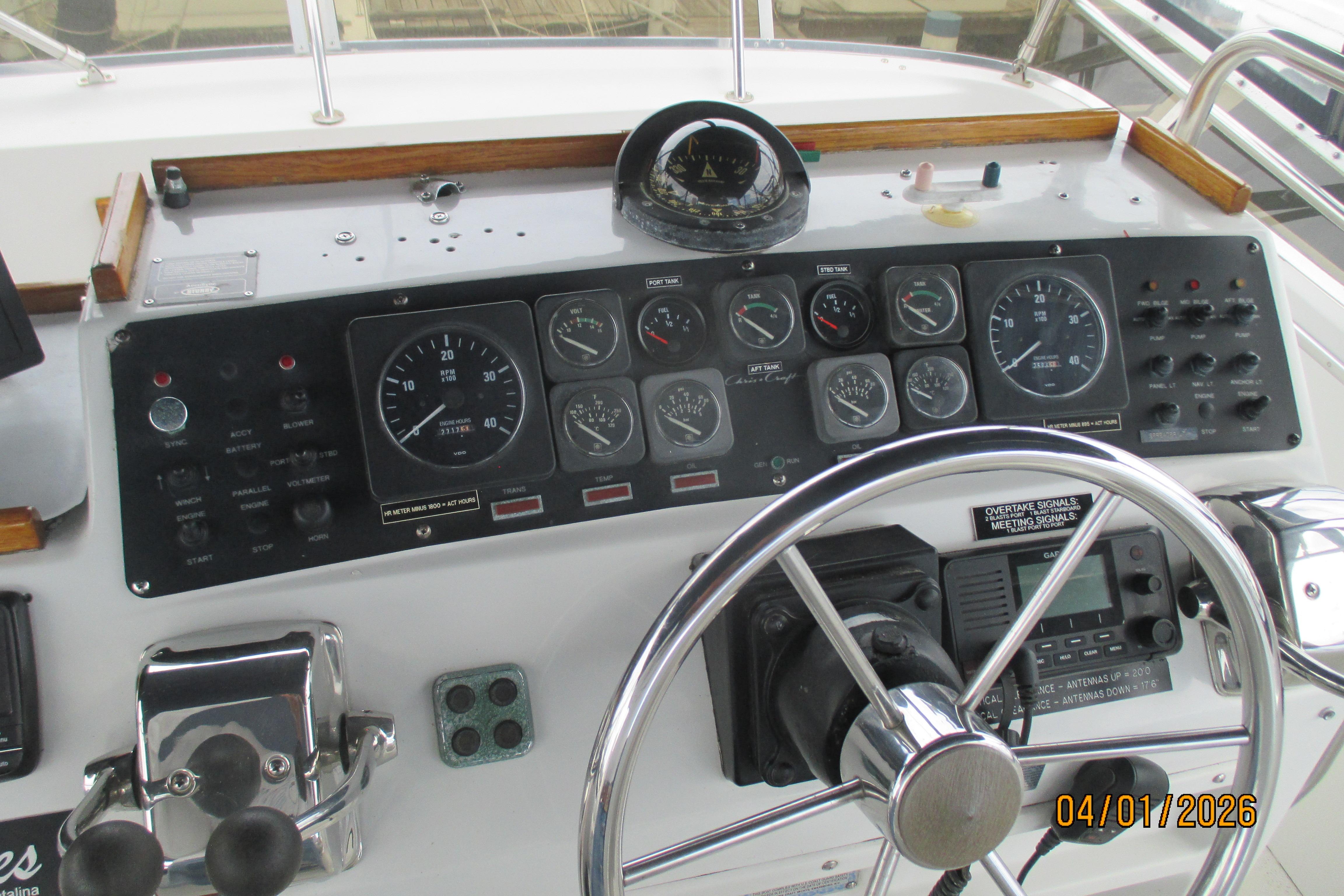 Control panel of a 1989 Chris Craft 427 Catalina boat with steering wheel and gauges.