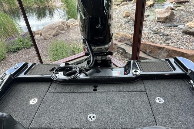 Nitro ZV21 Pro 2025 boat deck with motor, surrounded by rocks and greenery.
