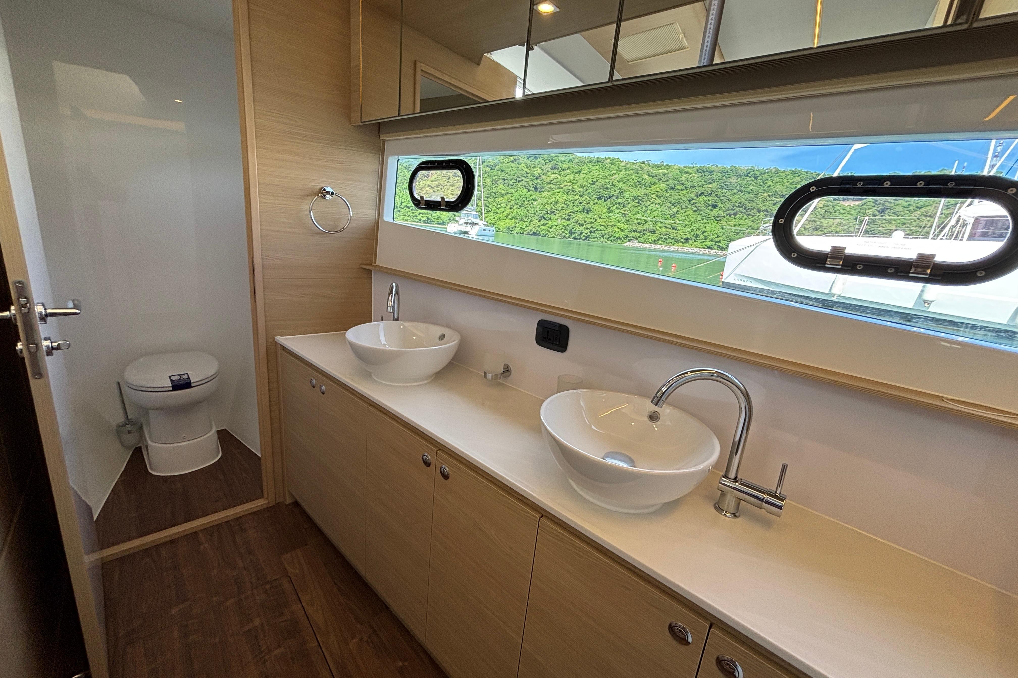 Luxurious bathroom on 2025 Aquila 54 Yacht with dual sinks and scenic window view.
