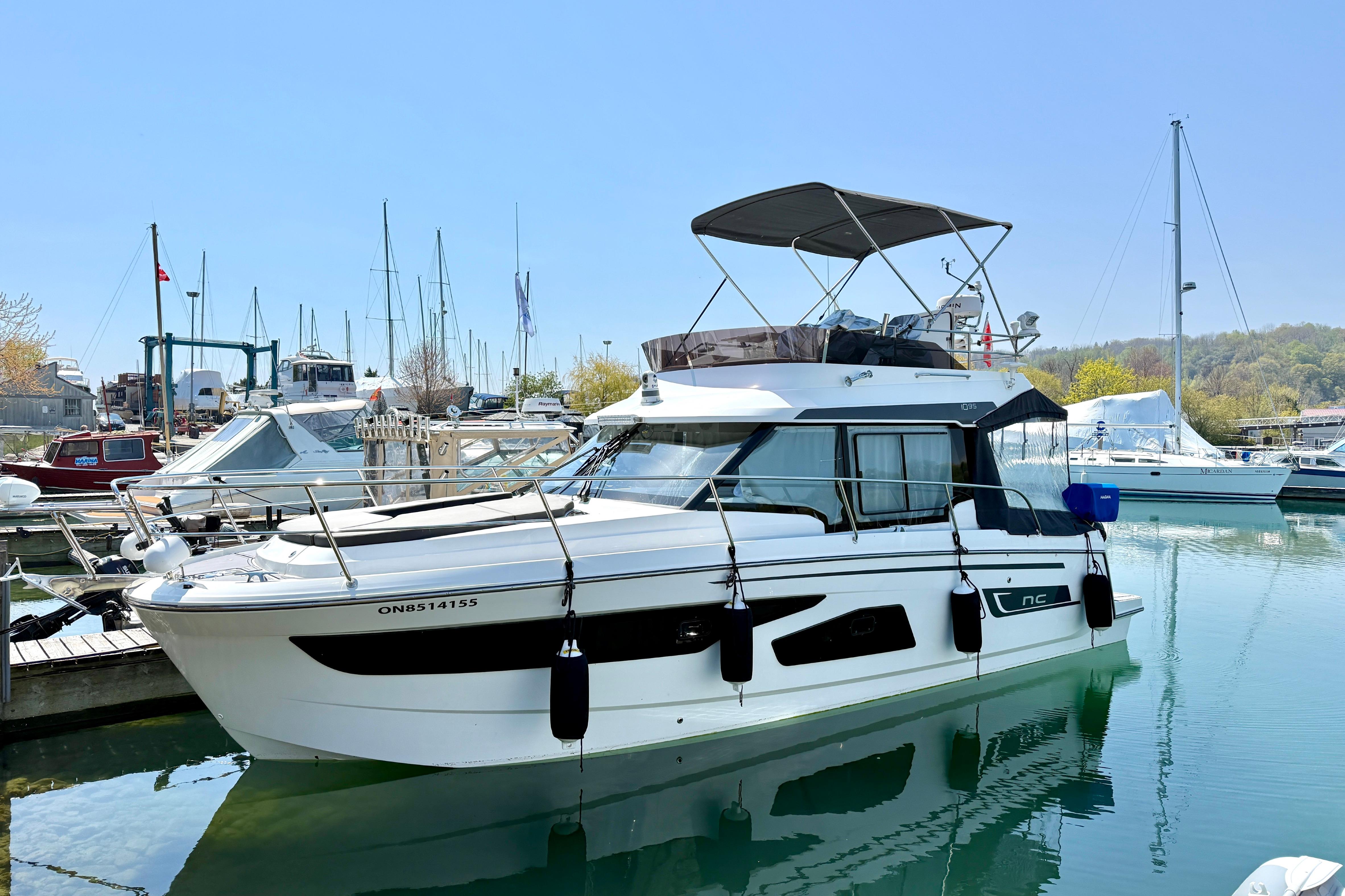 2022 Jeanneau NC 1095 Fly yacht docked in a marina under clear blue skies.