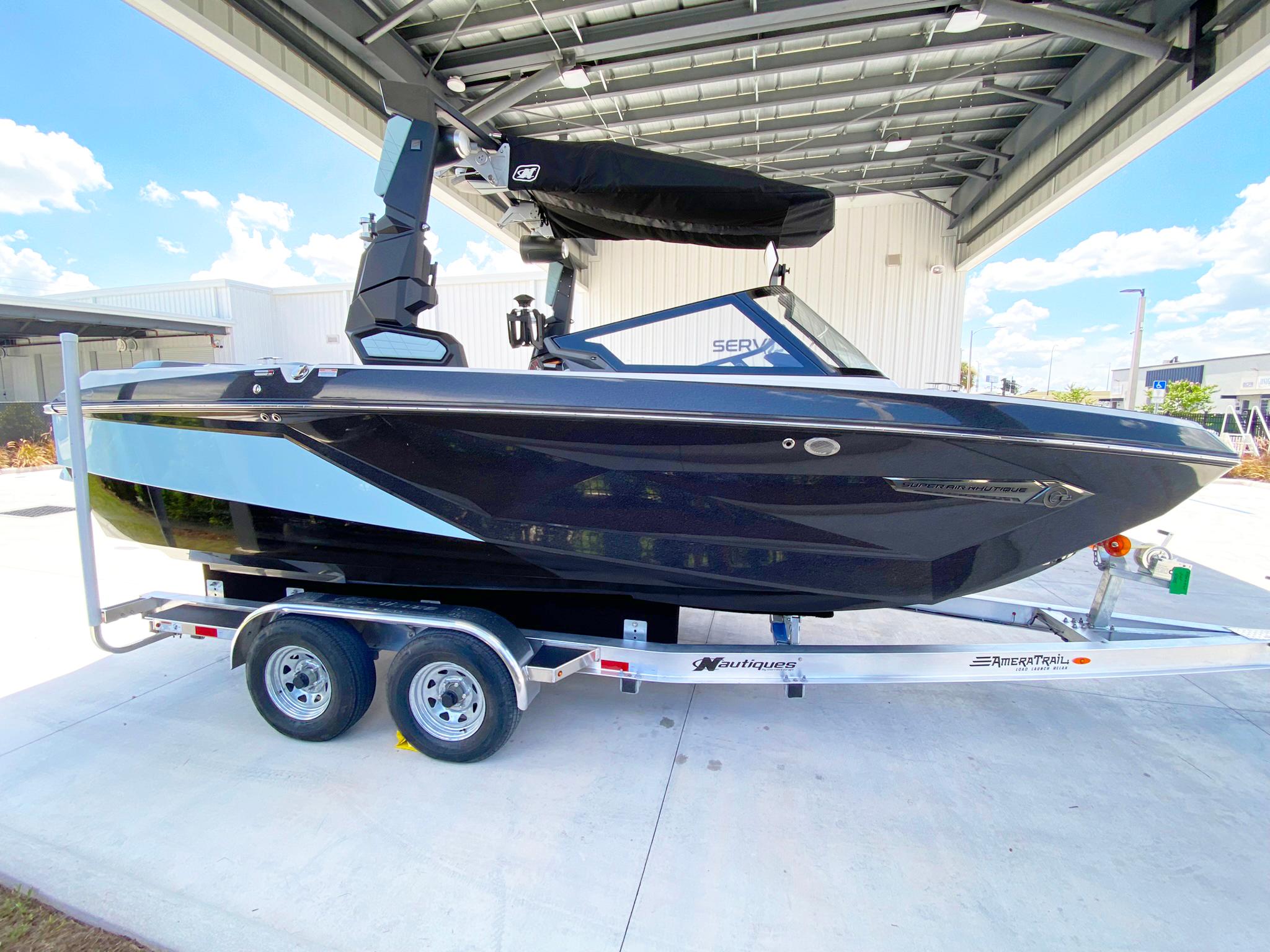 2024 Nautique Super Air Nautique G21 boat on trailer under a metal canopy.