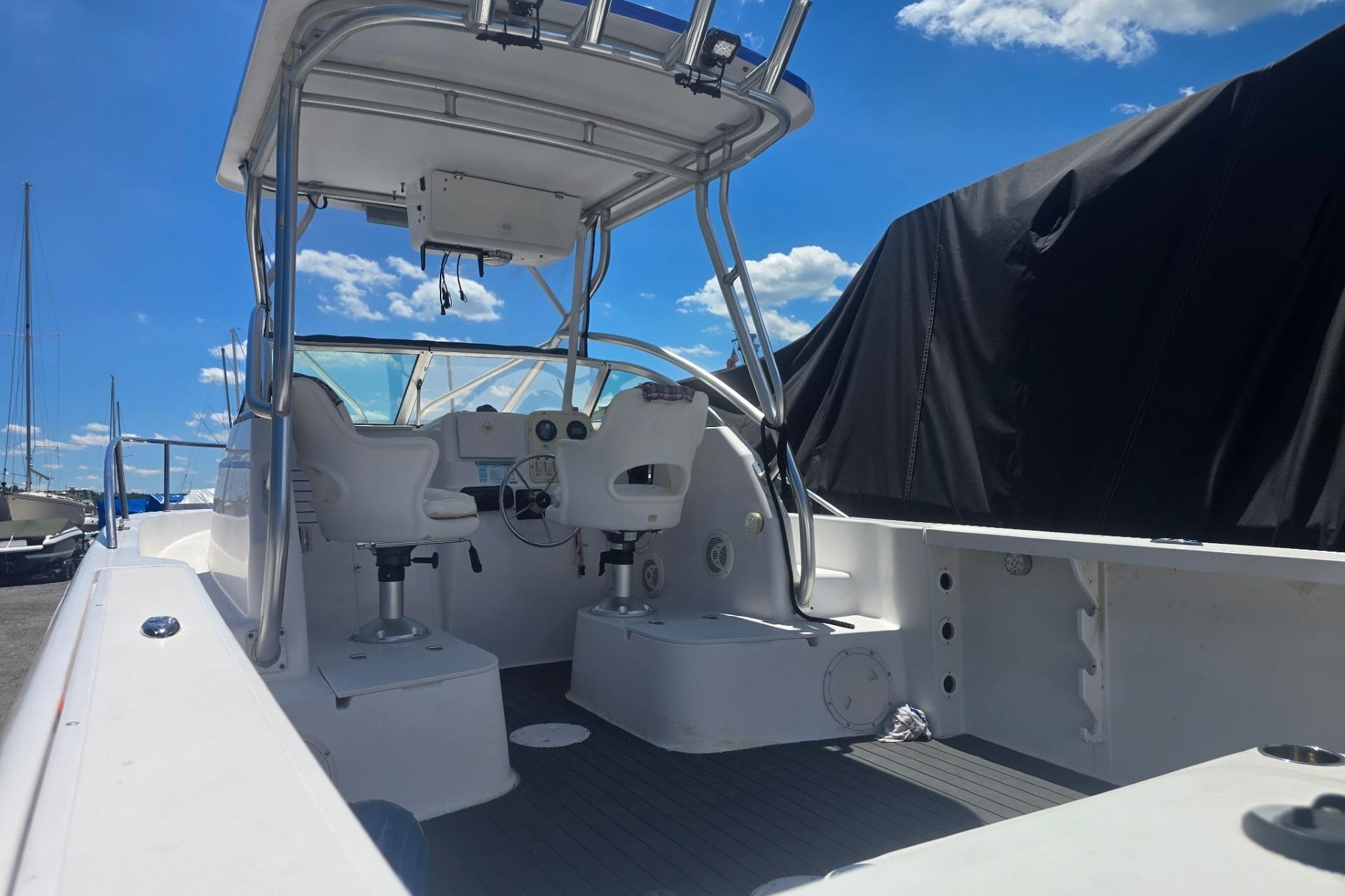2003 Pro-Line 22 Walkaround boat interior with helm and seating under a clear blue sky.
