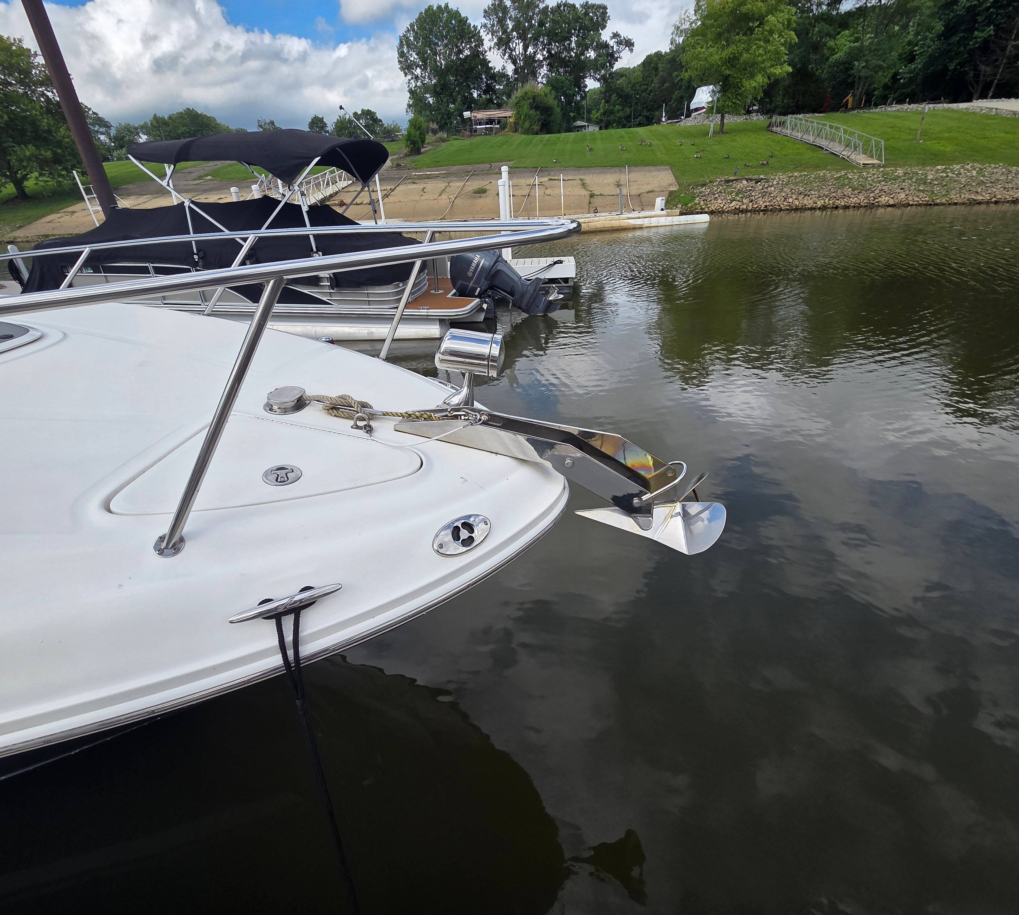 A 2005 Sea Ray Sundancer 260 docked by a calm water's edge.