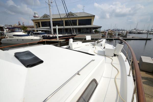 A 1980 Hatteras 53 Yacht Fisherman docked in a marina. Other boats and a building are visible in the background.