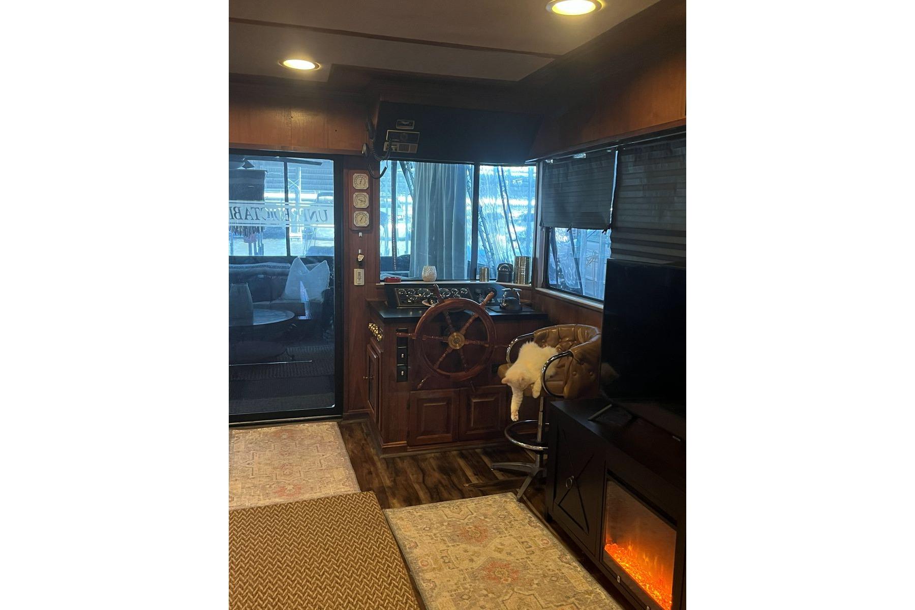Interior of a 1985 Sumerset 18x81 houseboat with helm, cozy seating, and fireplace.