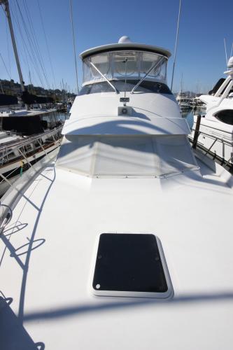 A 1994 Hatteras 52 Cockpit Motor Yacht docked in a marina, surrounded by other boats.