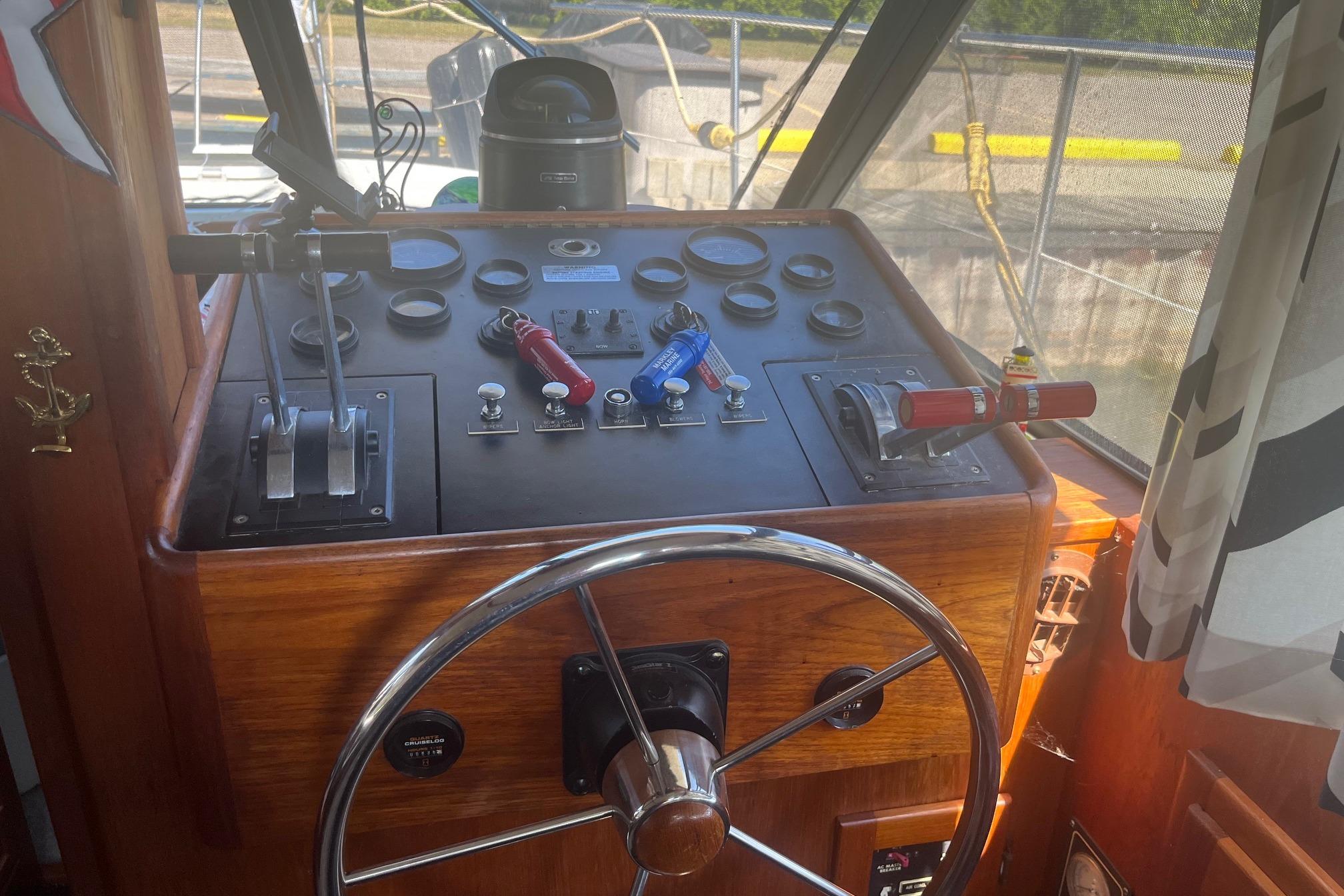 Control panel of a 1990 Cooper Prowler 35 boat with steering wheel and throttle levers.