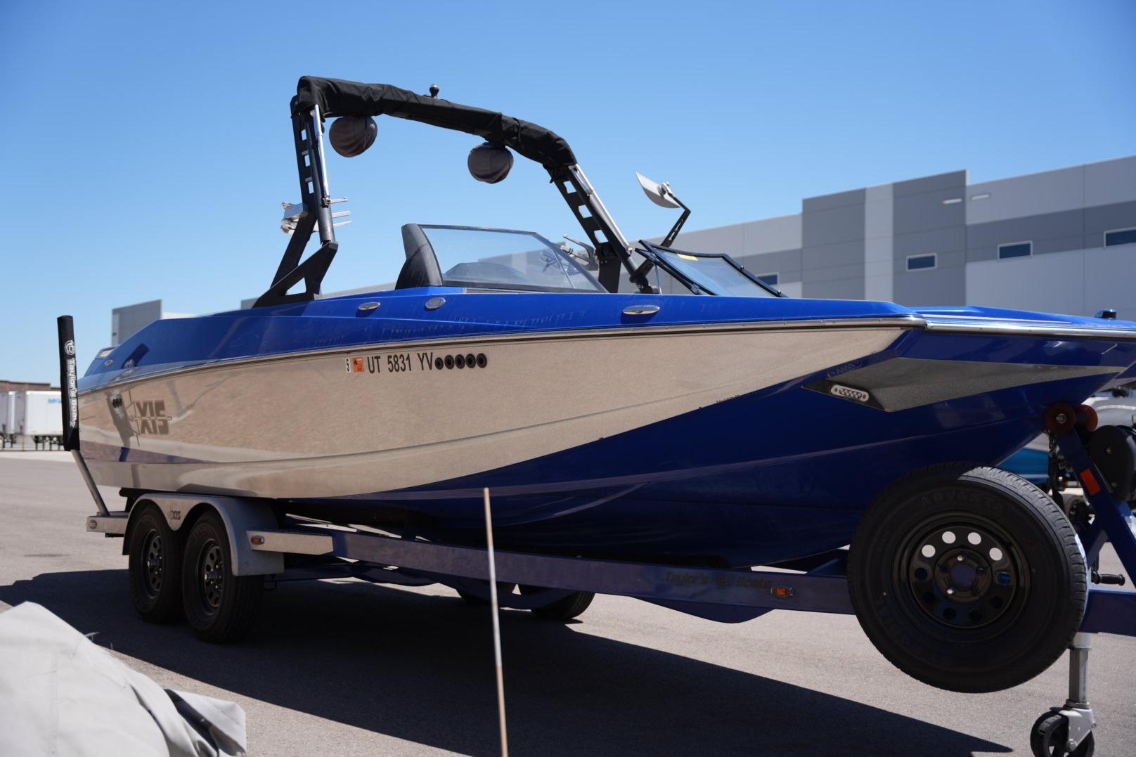 2015 Axis A24 boat on trailer, blue and silver, parked outdoors.
