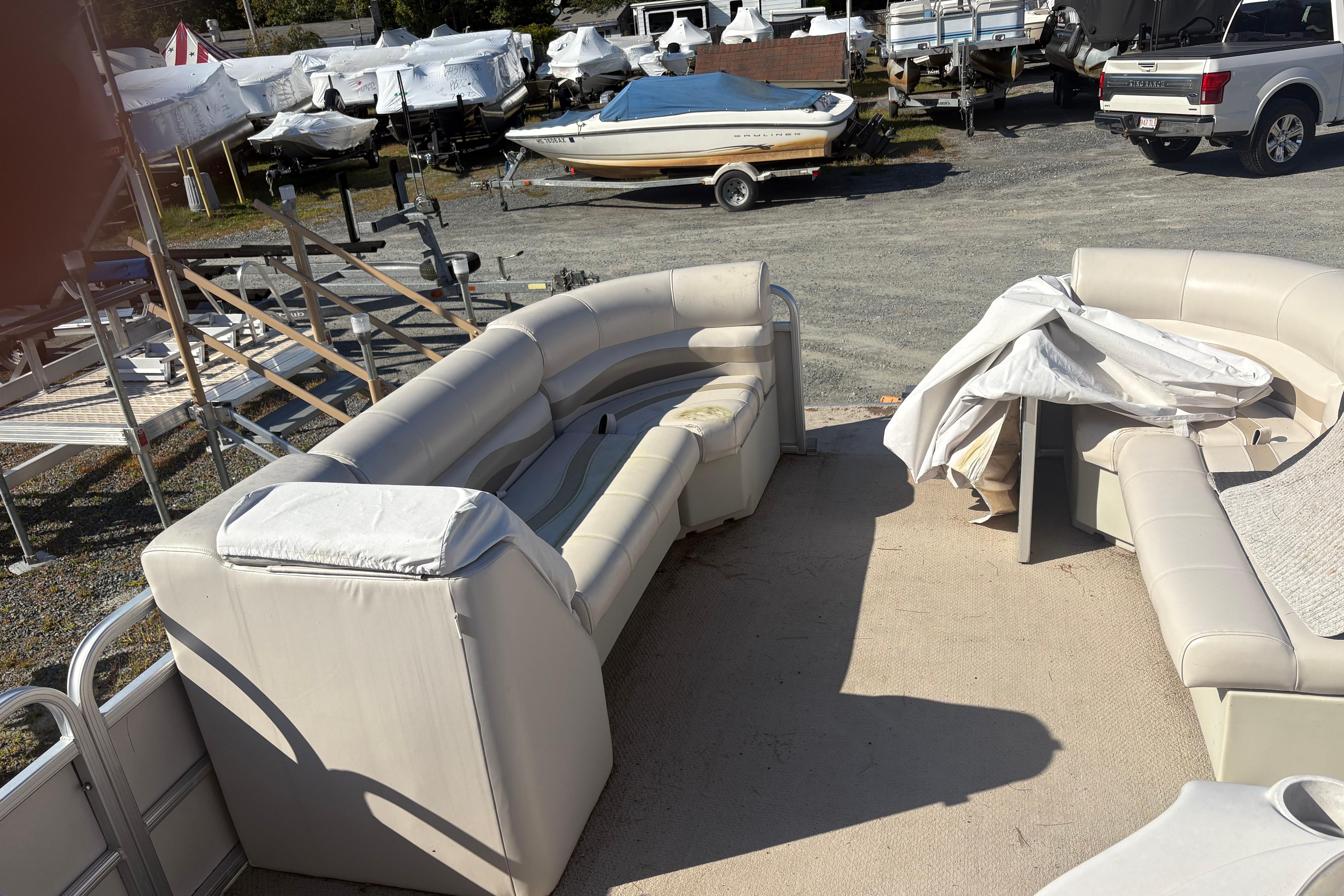 2003 Aqua Patio 200RE pontoon boat with beige seating in a boatyard.