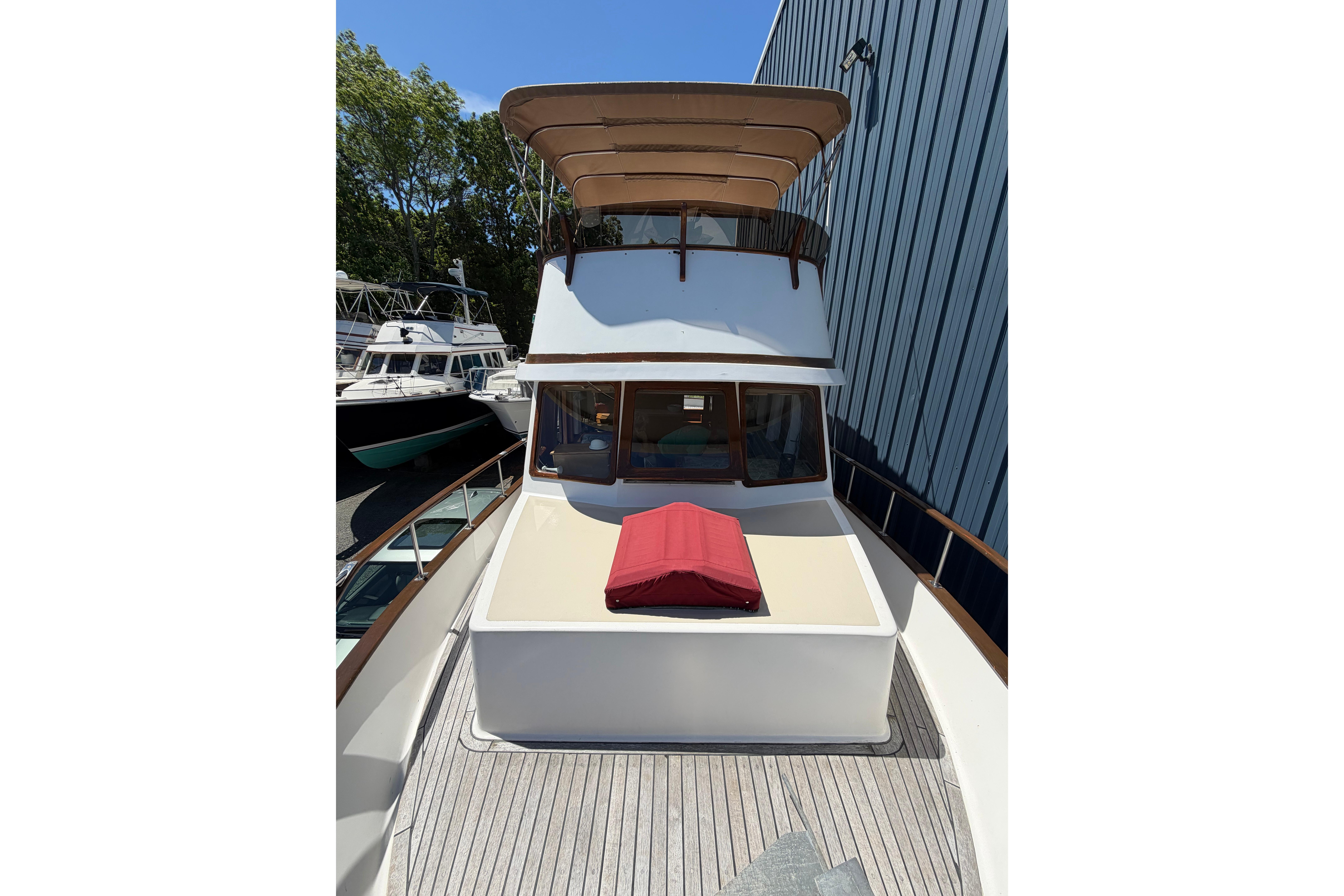 1987 Marine Trader 36 yacht with sun deck and canopy, docked near other boats.