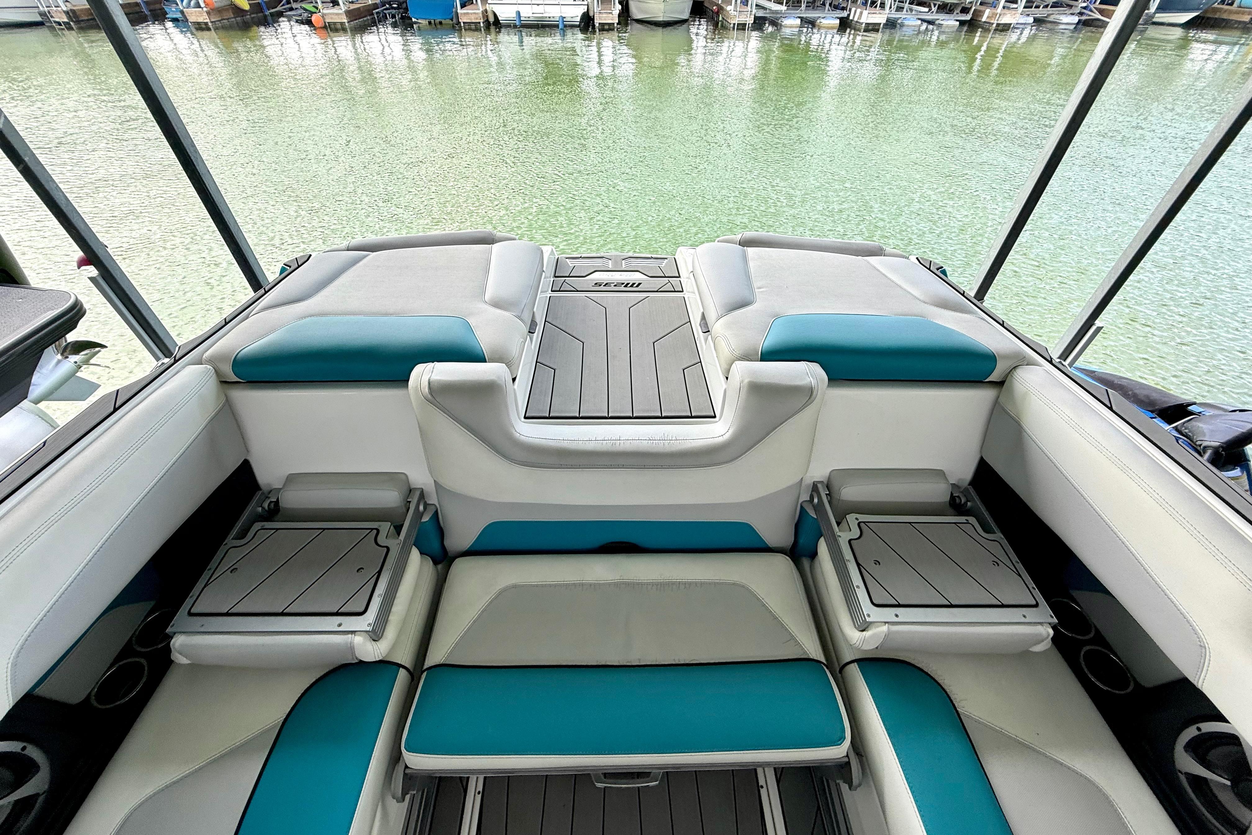 2017 Malibu M235 boat interior with teal and gray seating, docked by the water.
