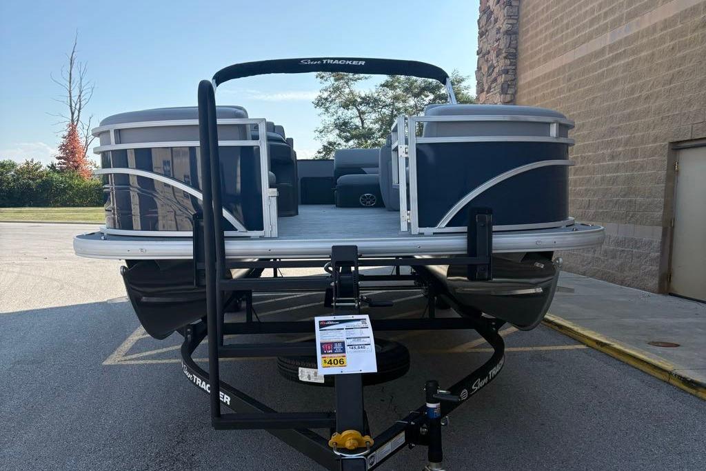 2026 Sun Tracker SportFish 22 DLX pontoon boat on trailer, parked outdoors.