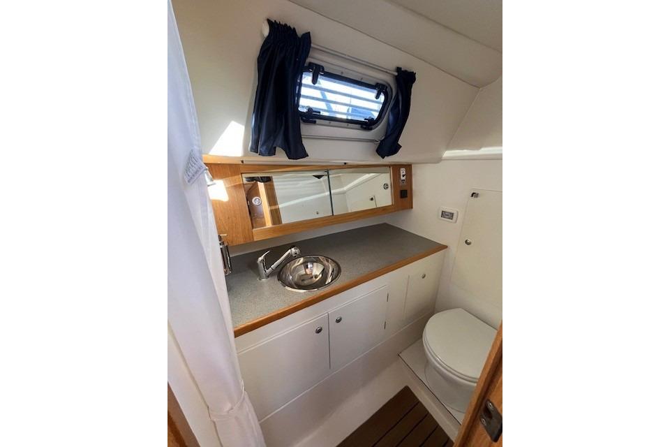 Compact boat bathroom with sink, mirror, and toilet in a 2009 Maxi 1060 model.